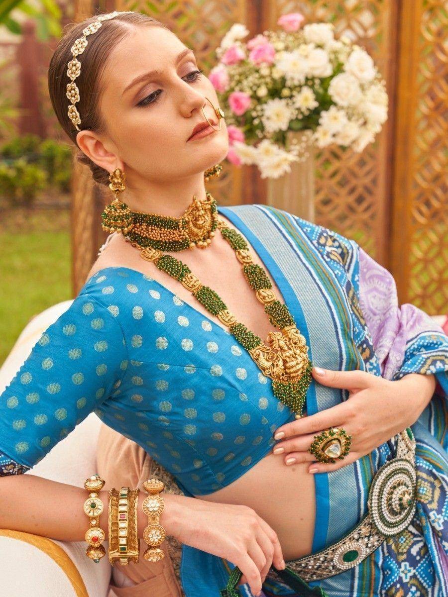 Elegant woman in blue polka dot blouse and ethnic saree with green gold jewelry