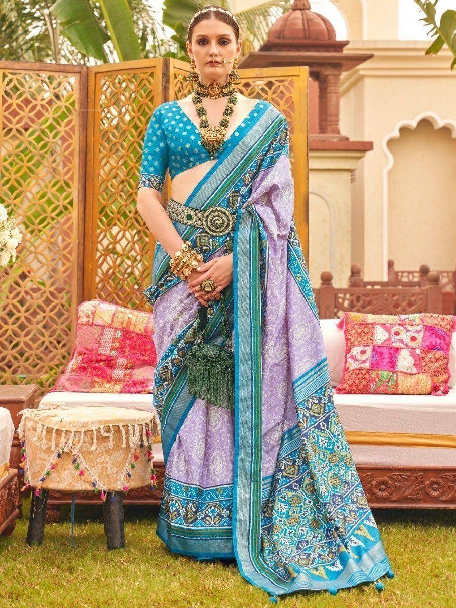 Woman in blue and lavender printed saree with gold jewelry, ethnic Indian wear for festive occasions