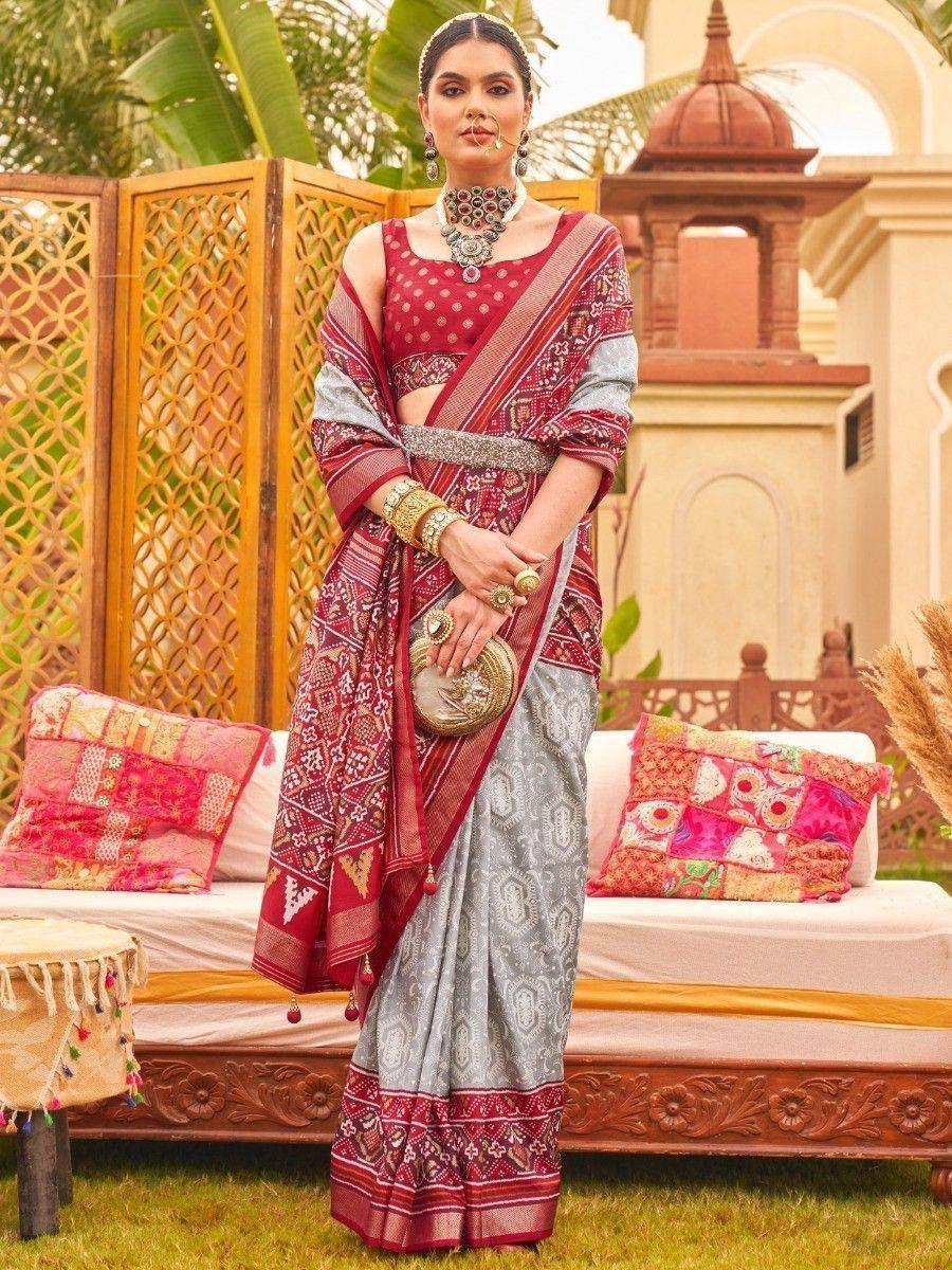 Woman in red and silver ethnic saree with intricate patterns, traditional jewelry, and ornate outdoor setting