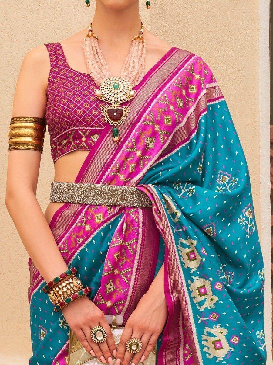 Vibrant pink and teal ethnic saree with intricate embroidery, paired with designer blouse and traditional jewelry