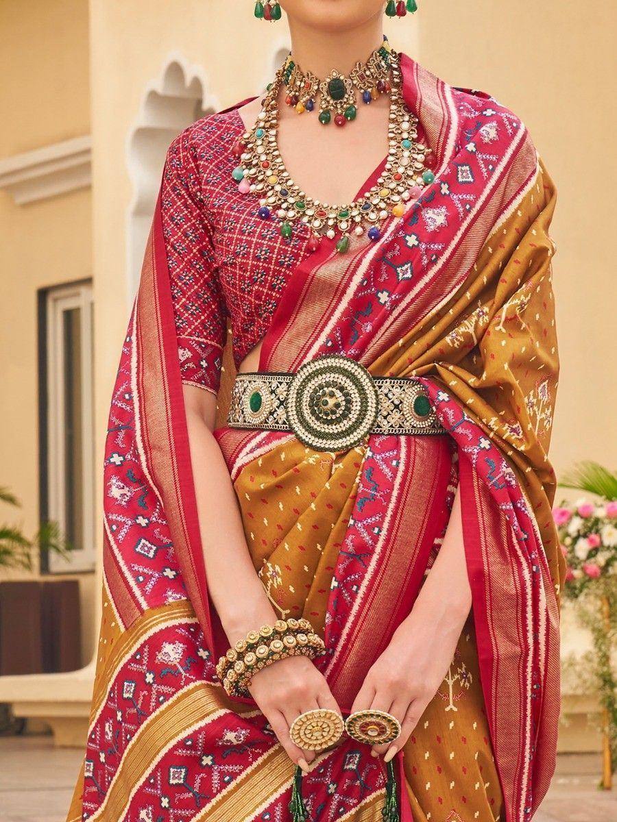 Red and gold ethnic saree with intricate embroidery, statement jewelry, and traditional belt for Indian wear