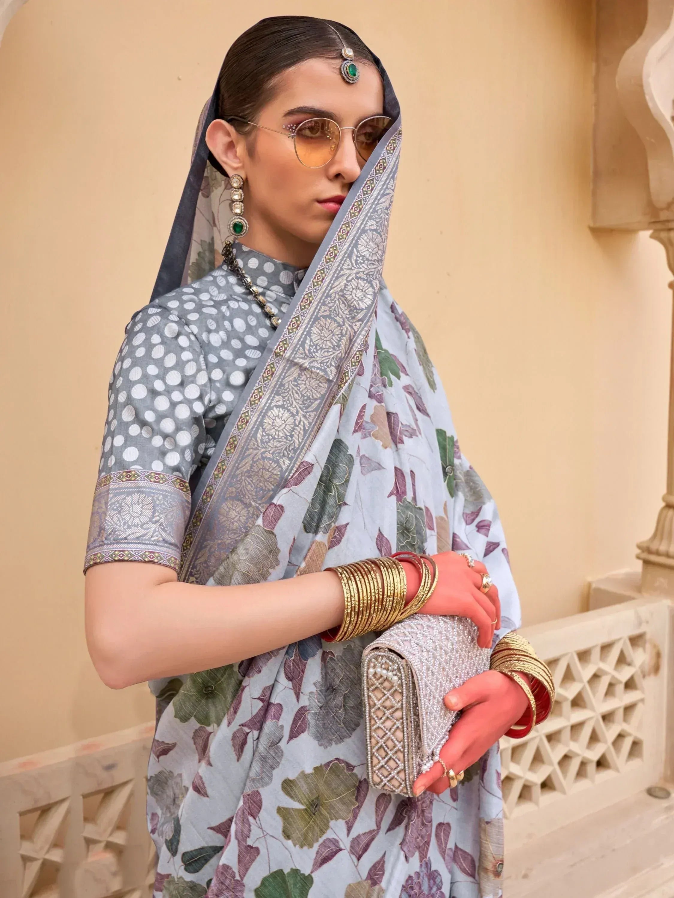 Woman in grey floral saree with polka dot blouse, traditional Indian ethnic wear, gold jewelry, and sunglasses