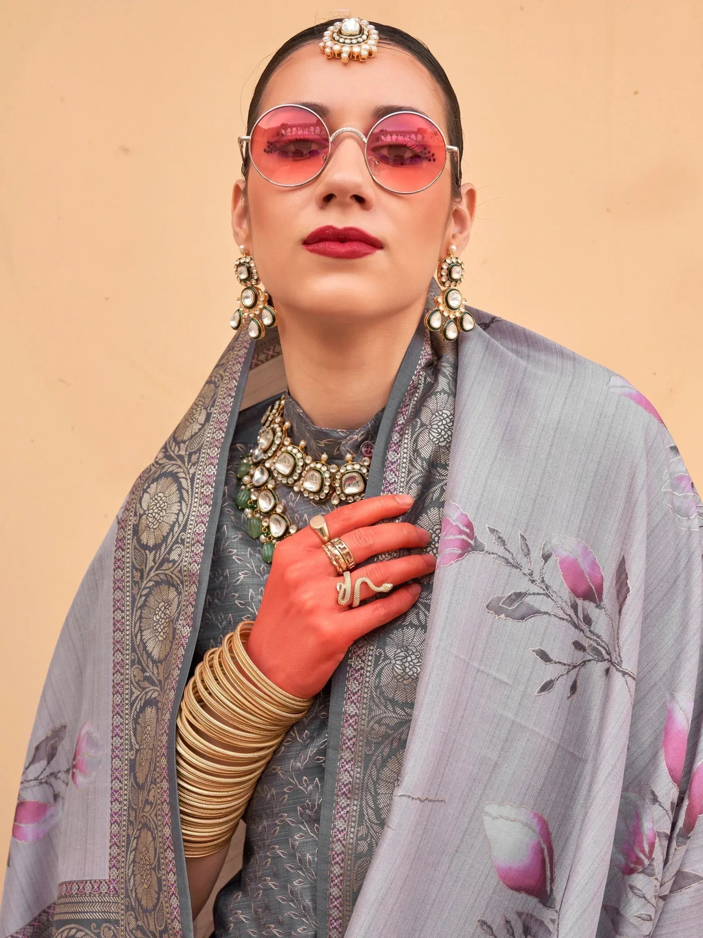 Woman in grey floral ethnic gown with pink sunglasses and traditional jewelry, perfect for Indian festive occasions.