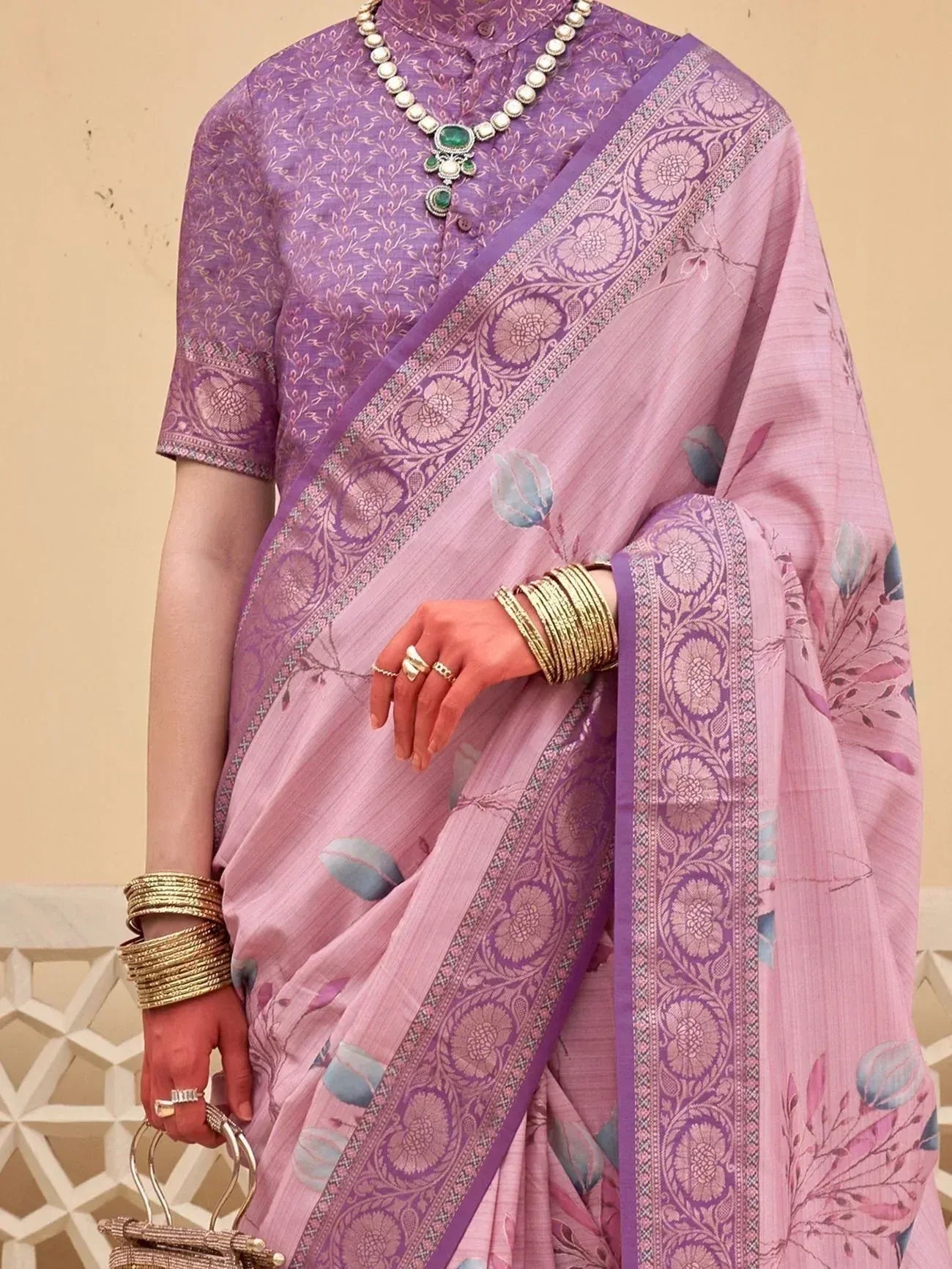 Pink and purple floral saree with embroidered border, paired with matching blouse and traditional jewelry