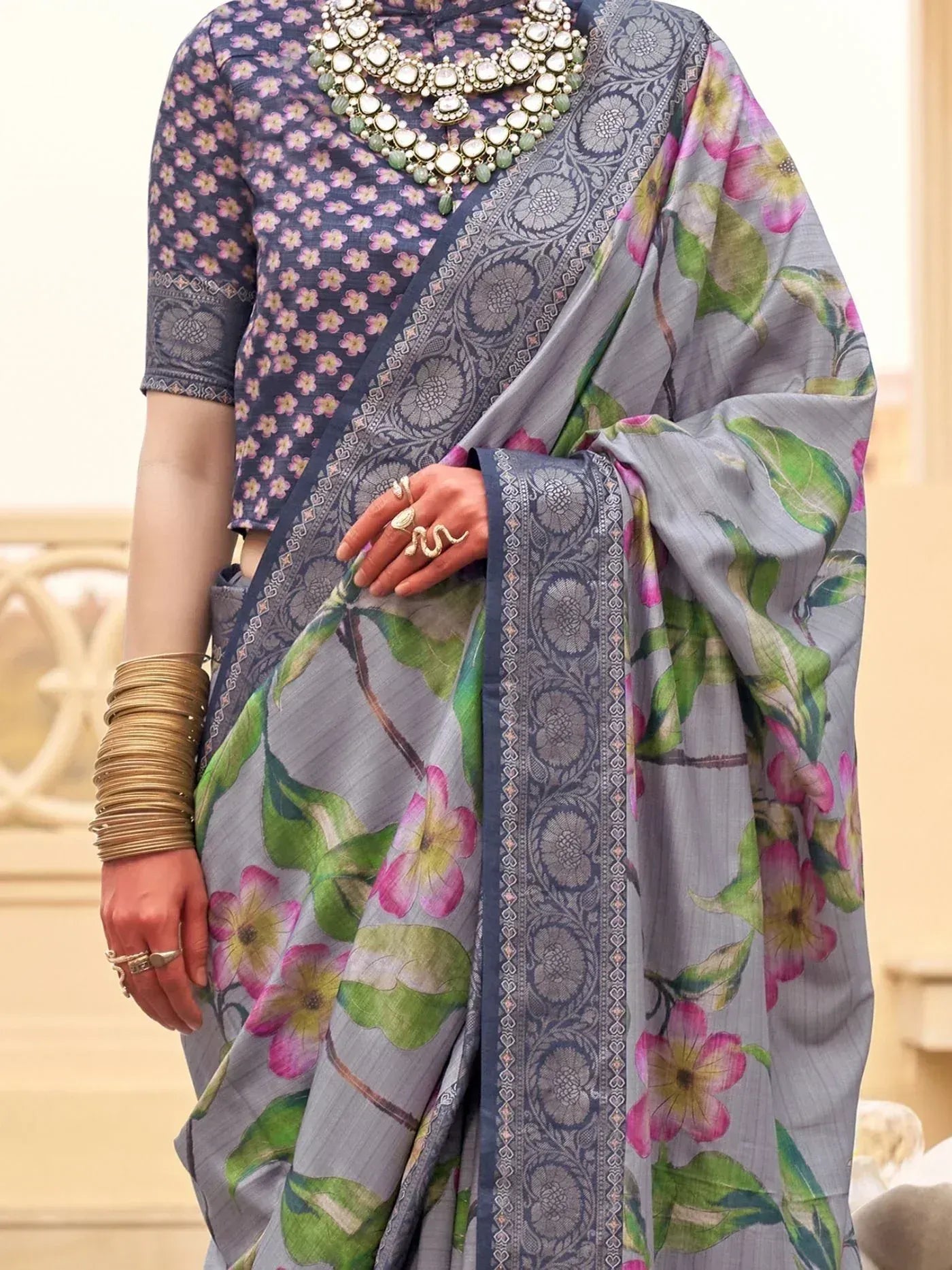 Grey floral print saree with intricate border, paired with matching blouse and traditional jewelry