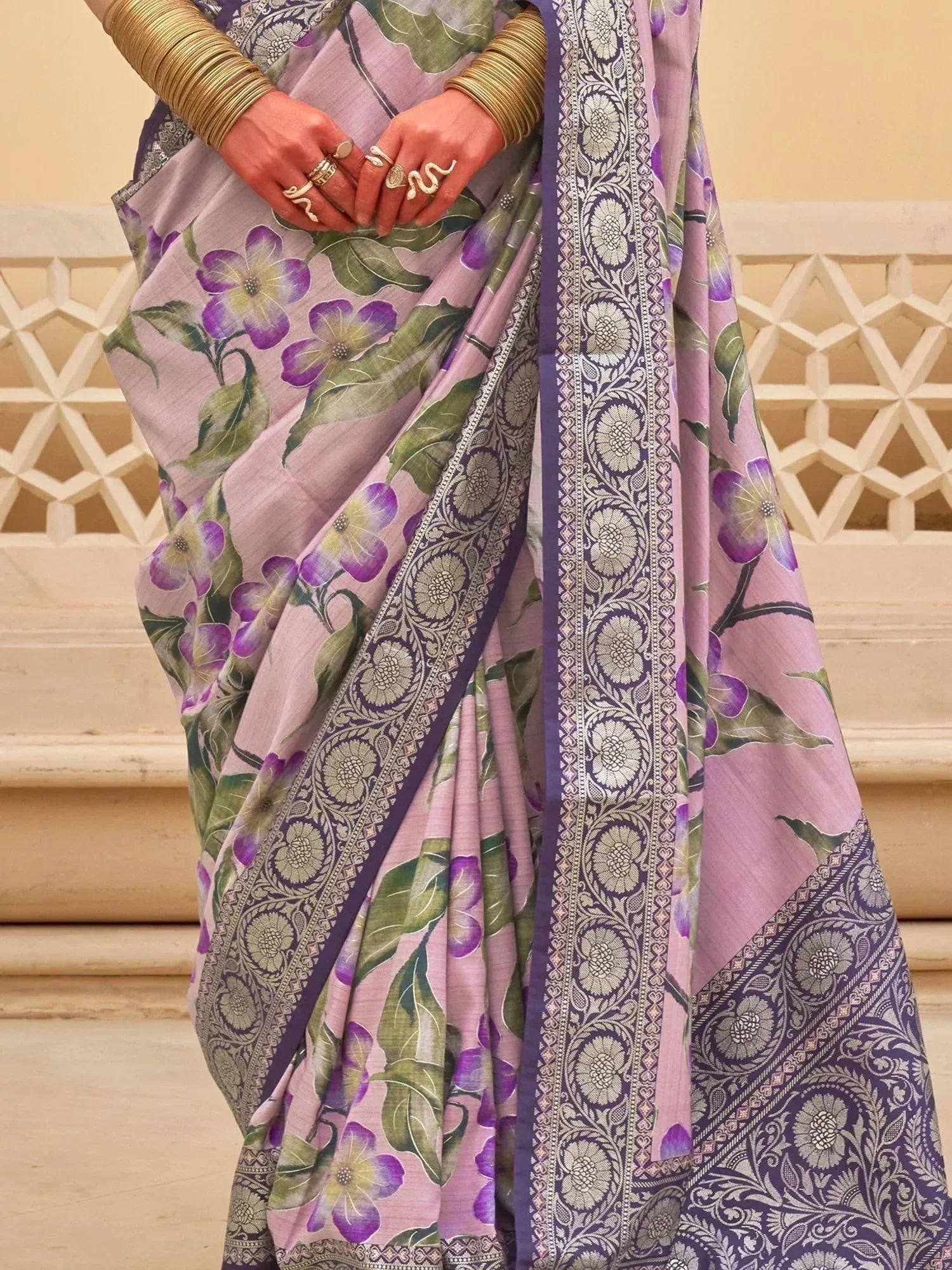 Purple floral printed saree with intricate border, styled with gold bangles and rings for ethnic wear