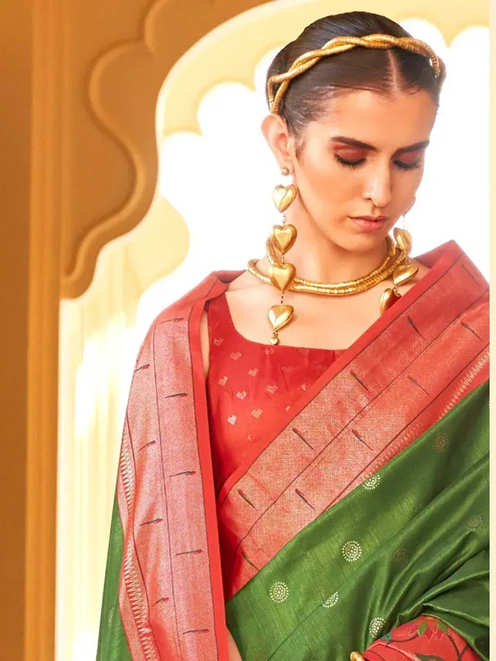 Woman in red and green ethnic saree with gold jewelry, traditional Indian attire