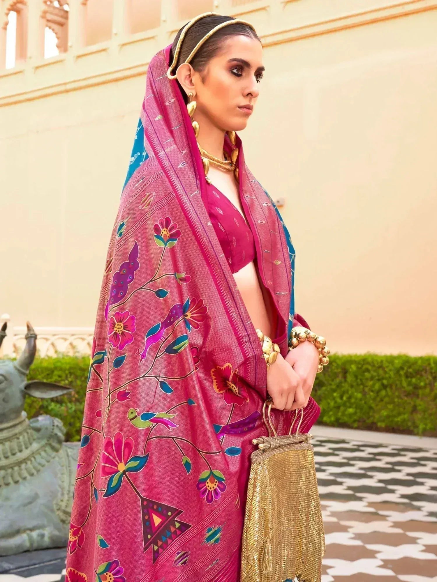 Woman in vibrant pink floral printed saree with gold jewelry, traditional Indian ethnic wear