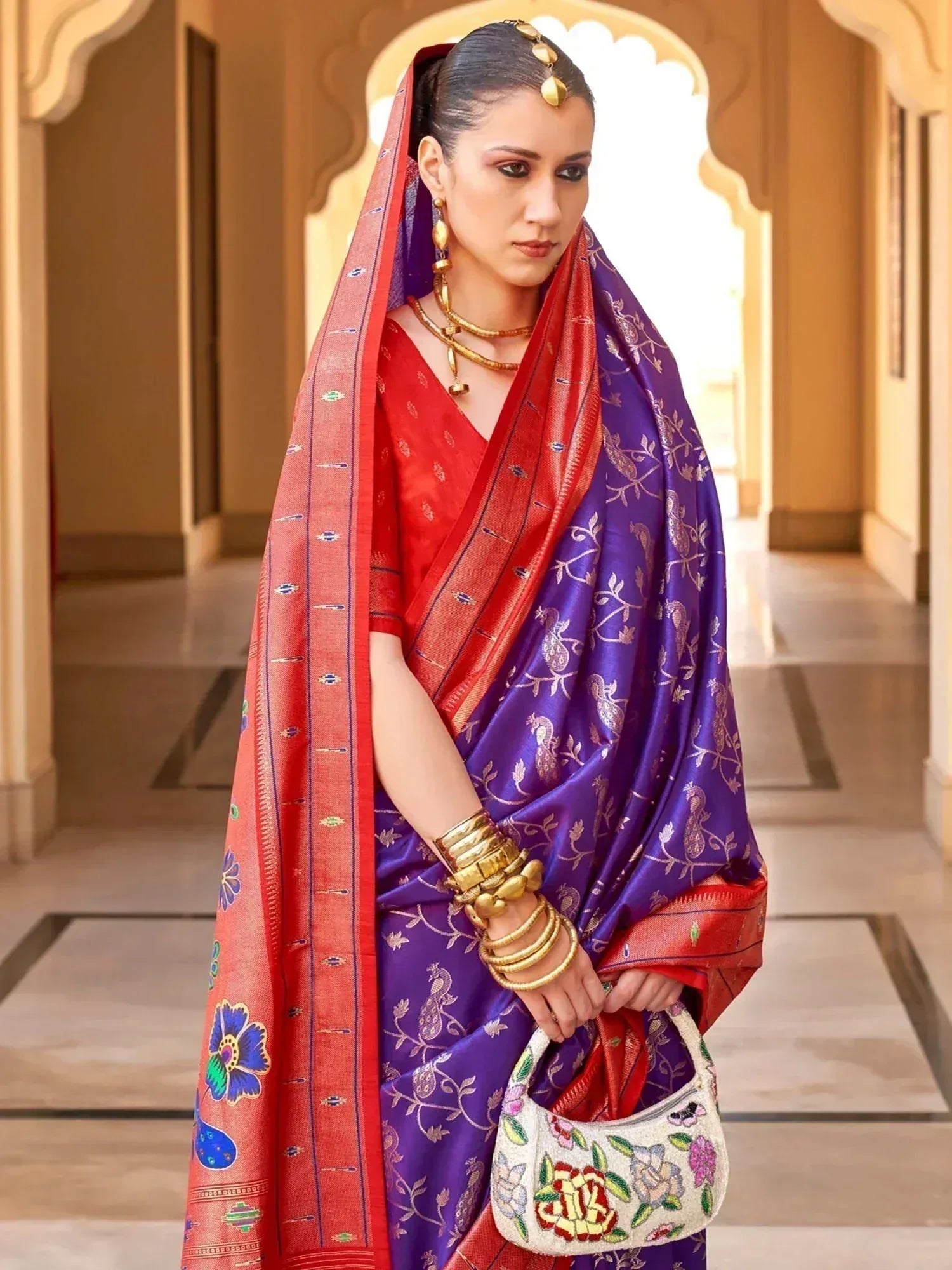 Woman in purple and red embroidered saree with gold jewelry, traditional Indian ethnic wear