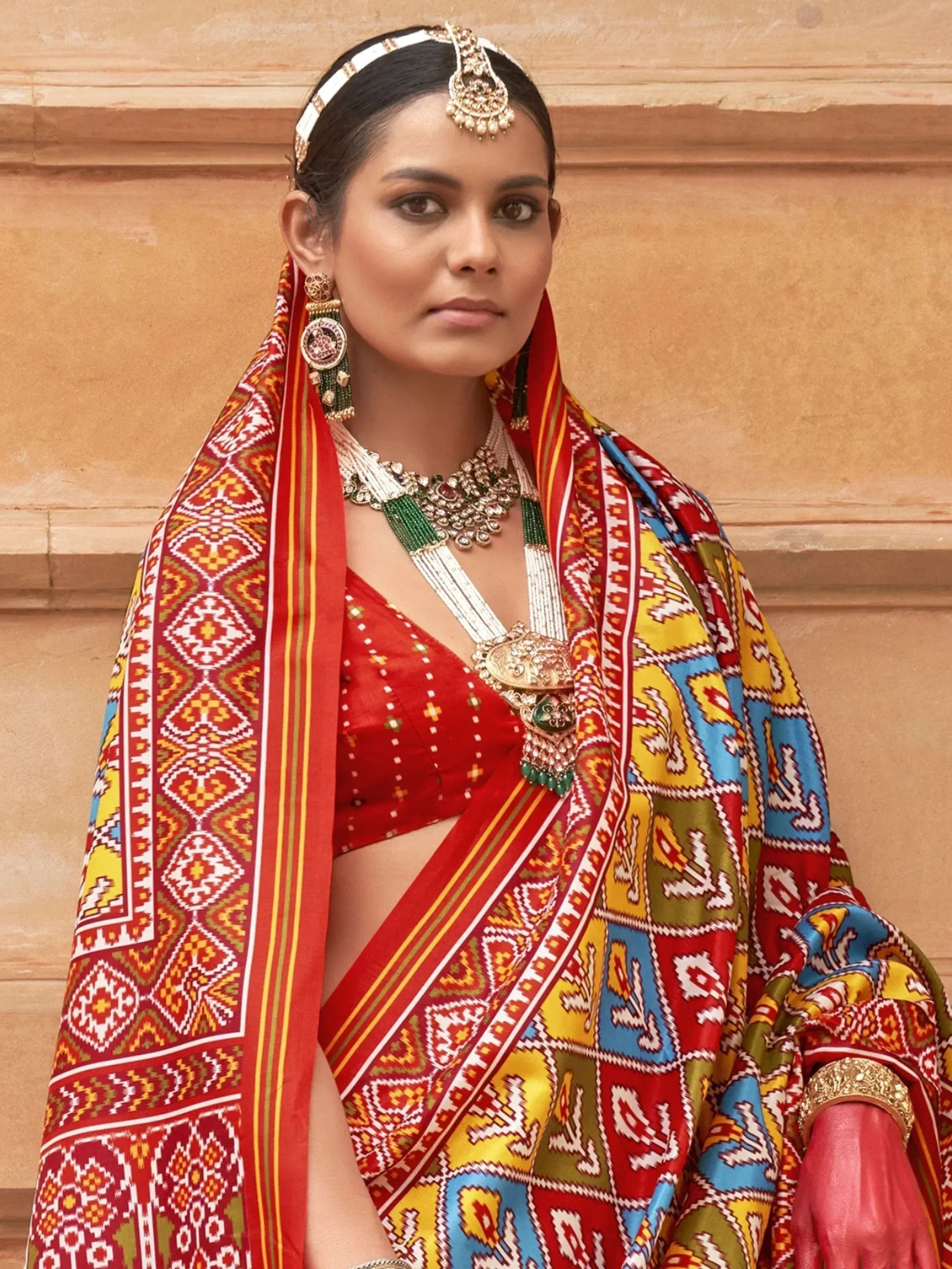 Woman in vibrant red and multicolor ethnic saree with traditional jewelry and headpiece