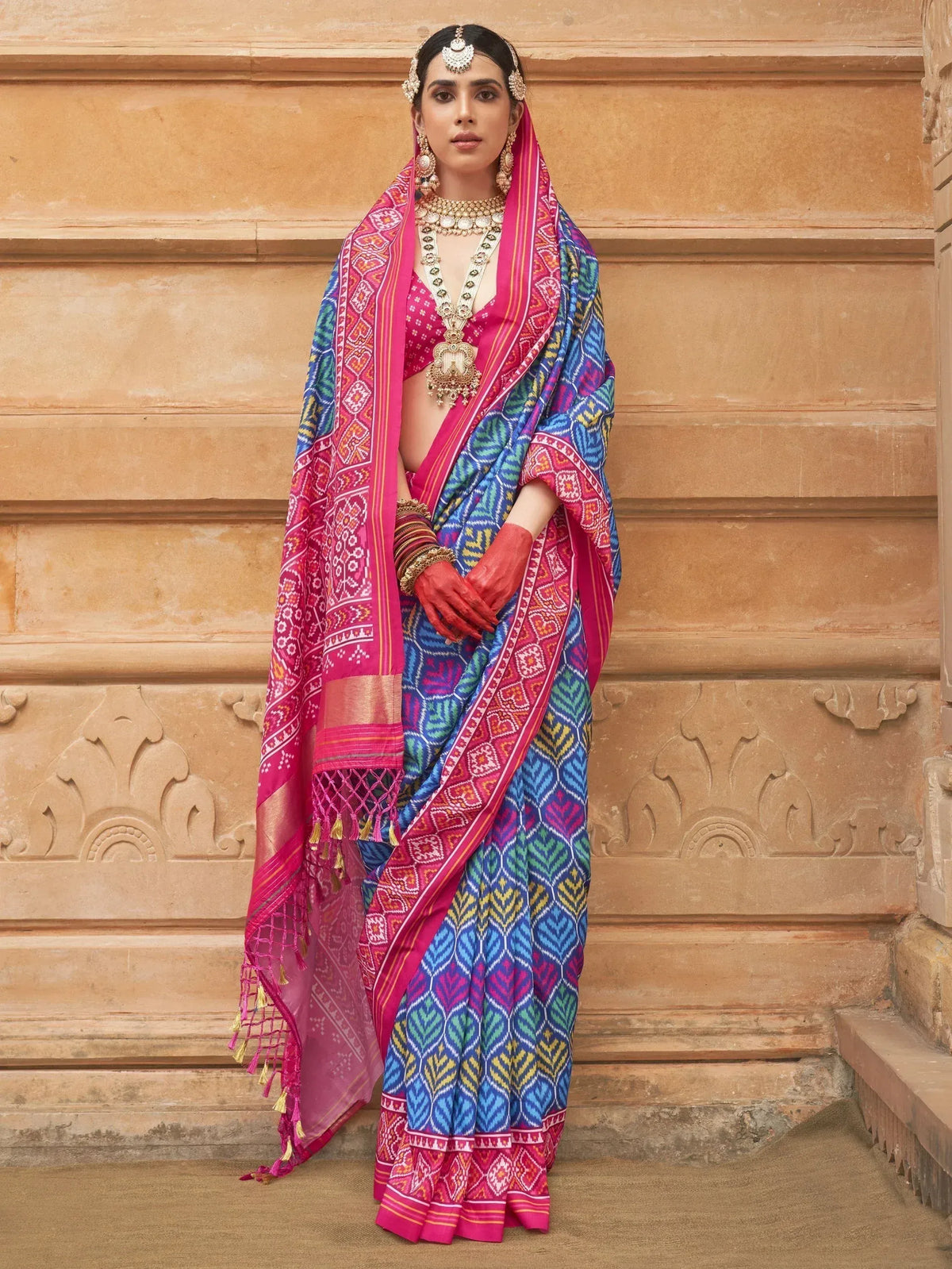 Vibrant pink and blue printed saree with ethnic jewelry, perfect for Indian festive occasions
