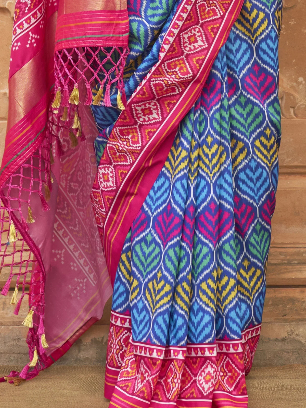 Vibrant blue and pink ikat saree with geometric patterns and tassel border, ideal for ethnic wear