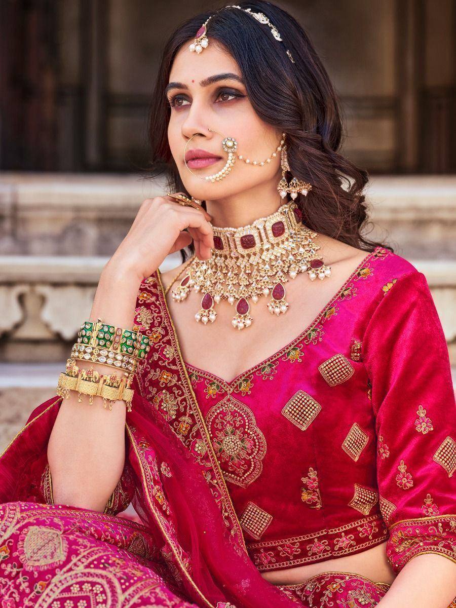 Woman in vibrant pink embroidered lehenga choli with gold jewelry, perfect for Indian ethnic wear occasions.