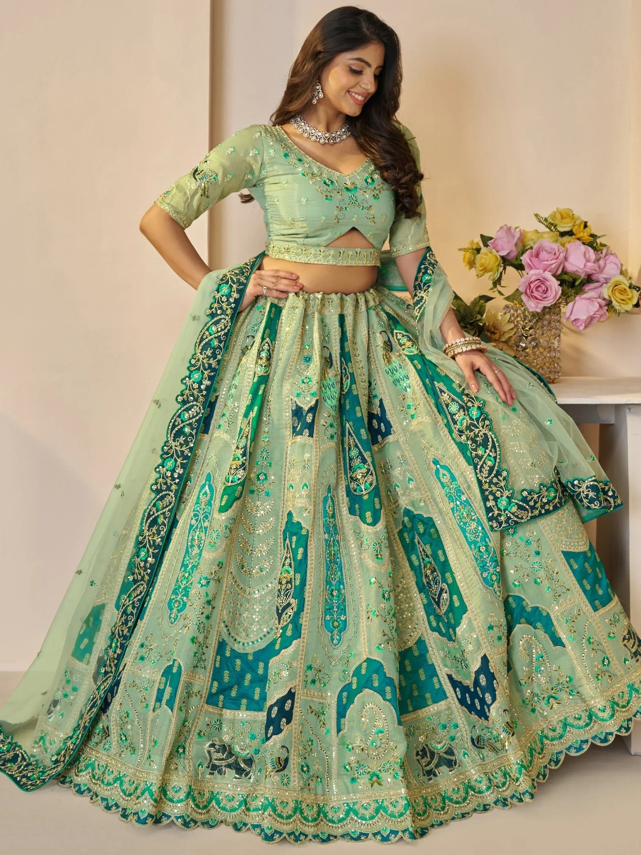 Mint green designer lehenga choli with heavy embroidery and peacock motifs, perfect for weddings and parties.