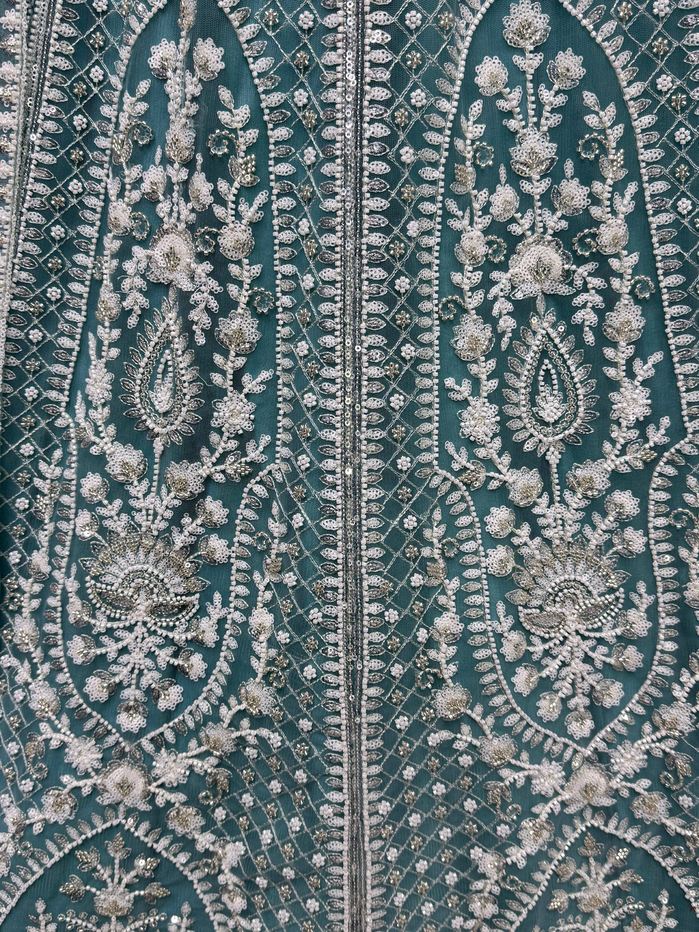 Teal ethnic gown with intricate silver floral embroidery and beadwork, perfect for Indian weddings or festive occasions.