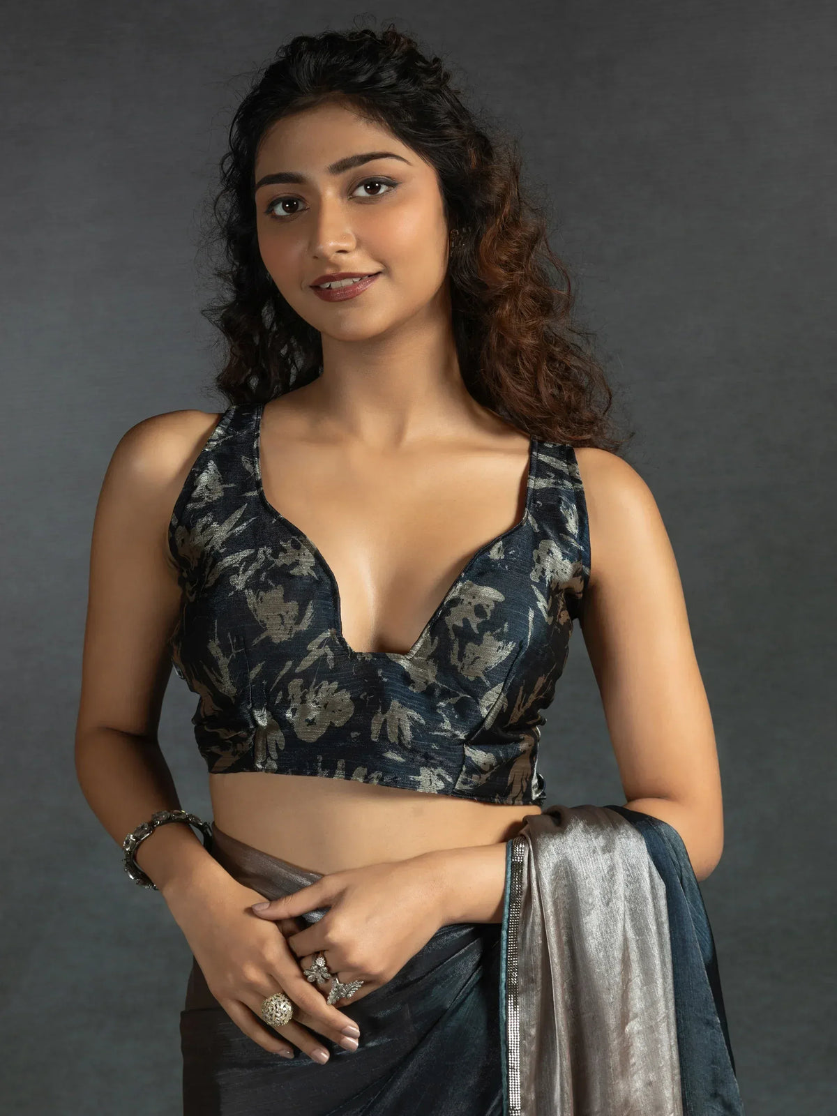 Woman in elegant dark blue floral saree with deep V-neck blouse, perfect for Indian ethnic wear occasions.
