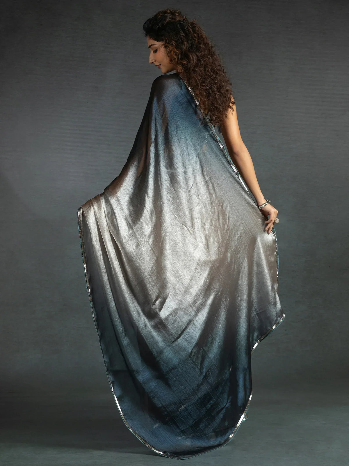 Woman in elegant silver-grey saree with shimmering border, showcasing Indian ethnic wear style