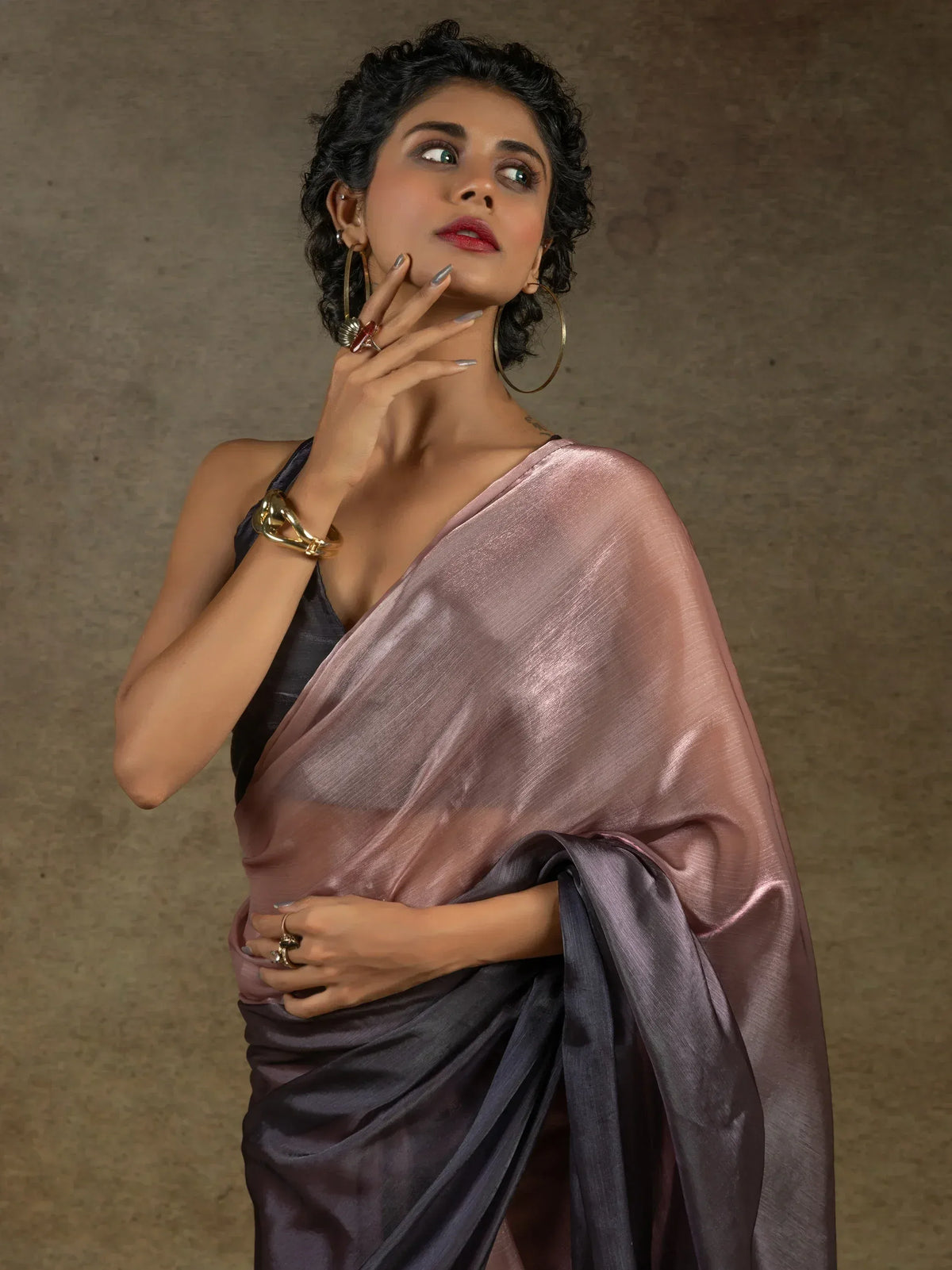 Woman in elegant pink and grey saree with gold jewelry, showcasing Indian ethnic wear