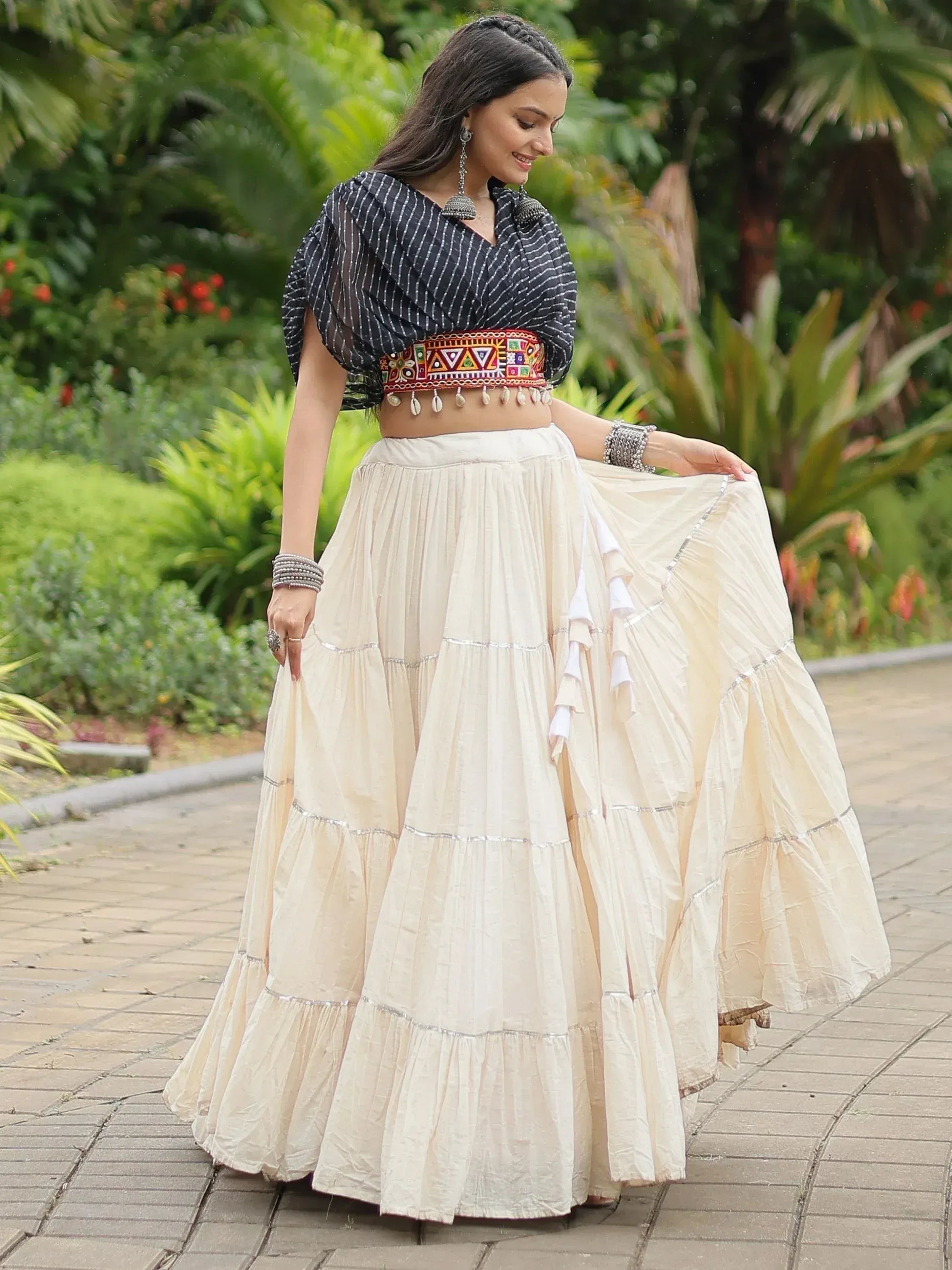 Elegant cream tiered lehenga with embroidered belt and black striped blouse, perfect for Indian ethnic wear.