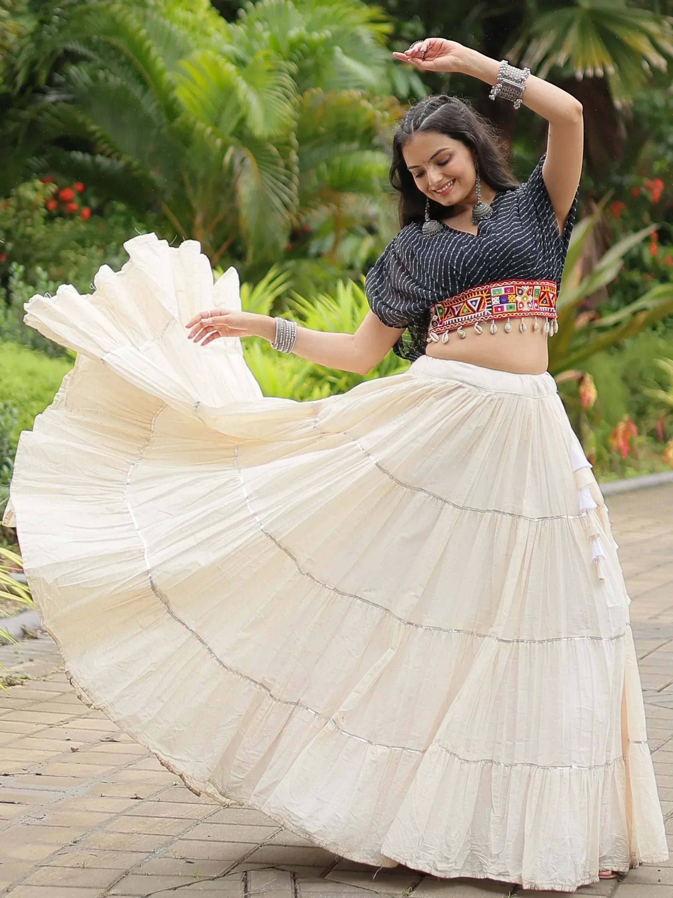 Woman dancing in ethnic Indian outfit with embroidered crop top and flowing cream skirt