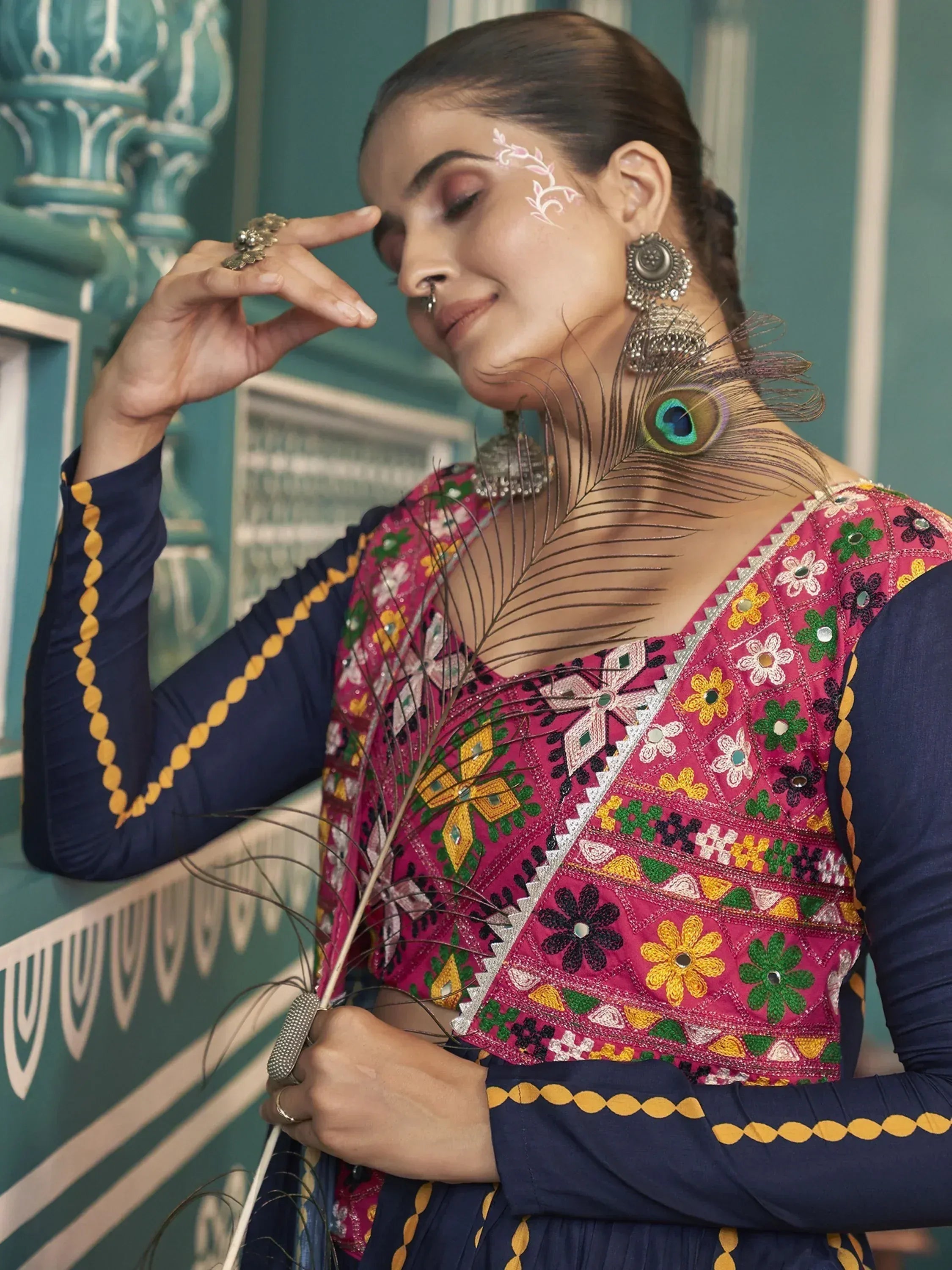 Woman in vibrant embroidered Indian ethnic wear with peacock feather accessory