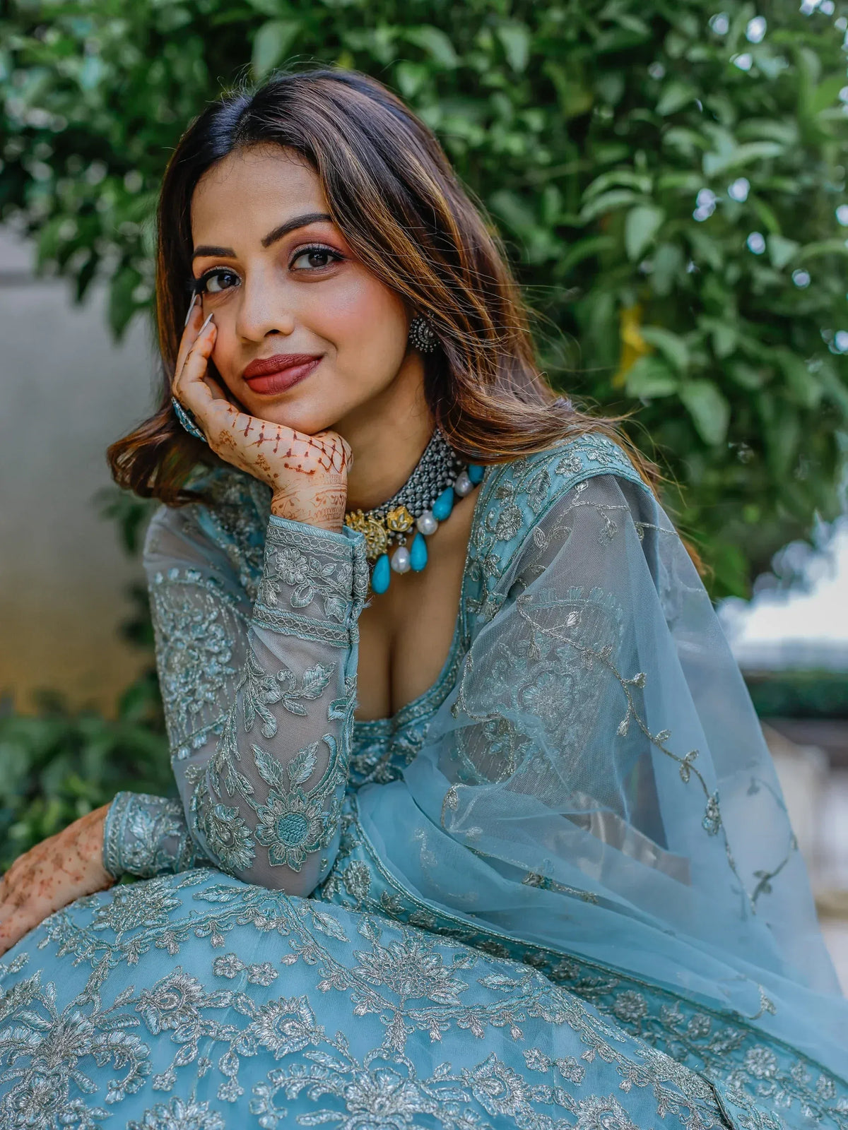 Woman in elegant blue embroidered lehenga choli with henna, perfect for Indian ethnic wear events
