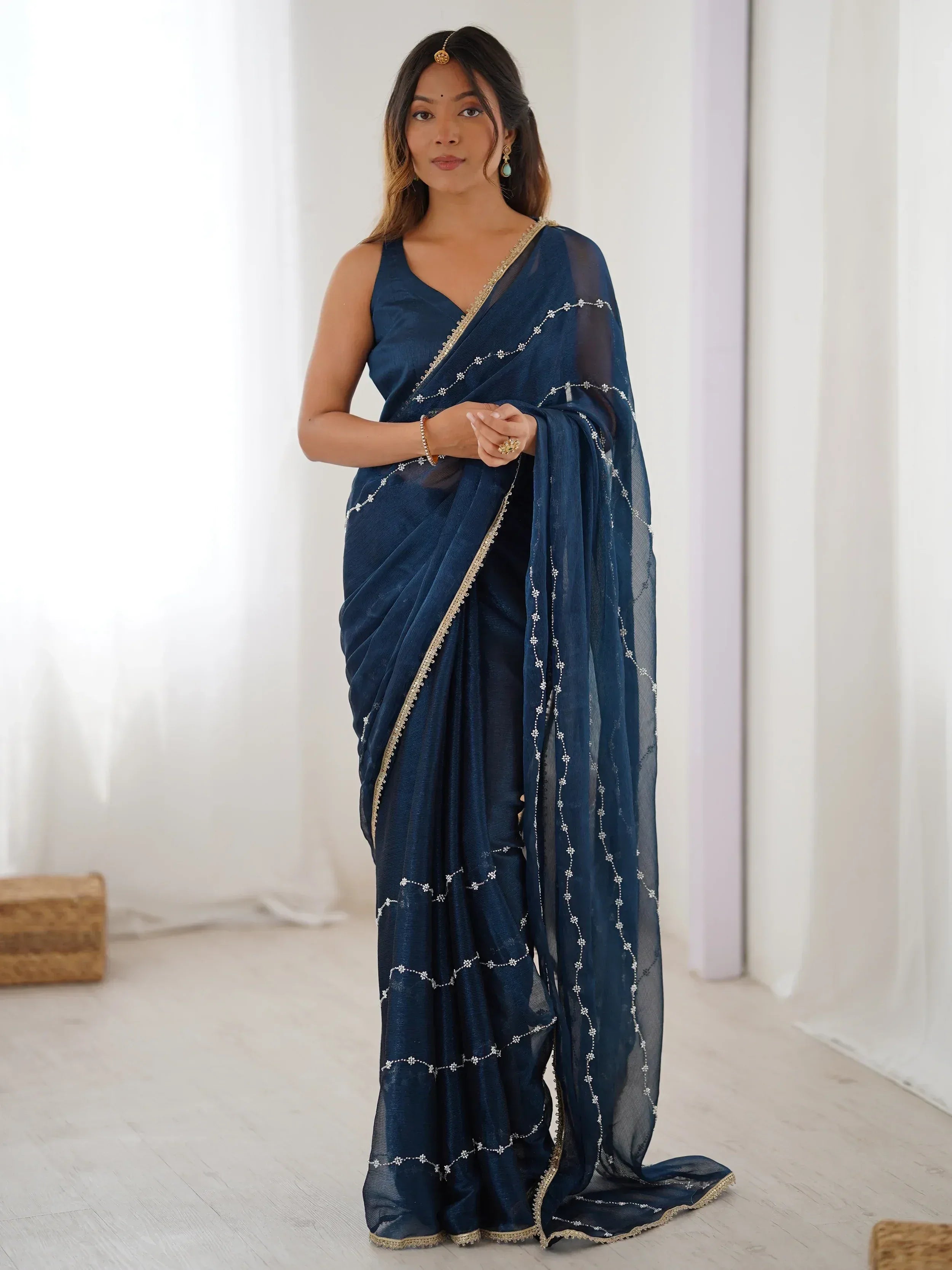 Navy blue embroidered saree with gold trim, styled with traditional Indian jewelry for ethnic wear