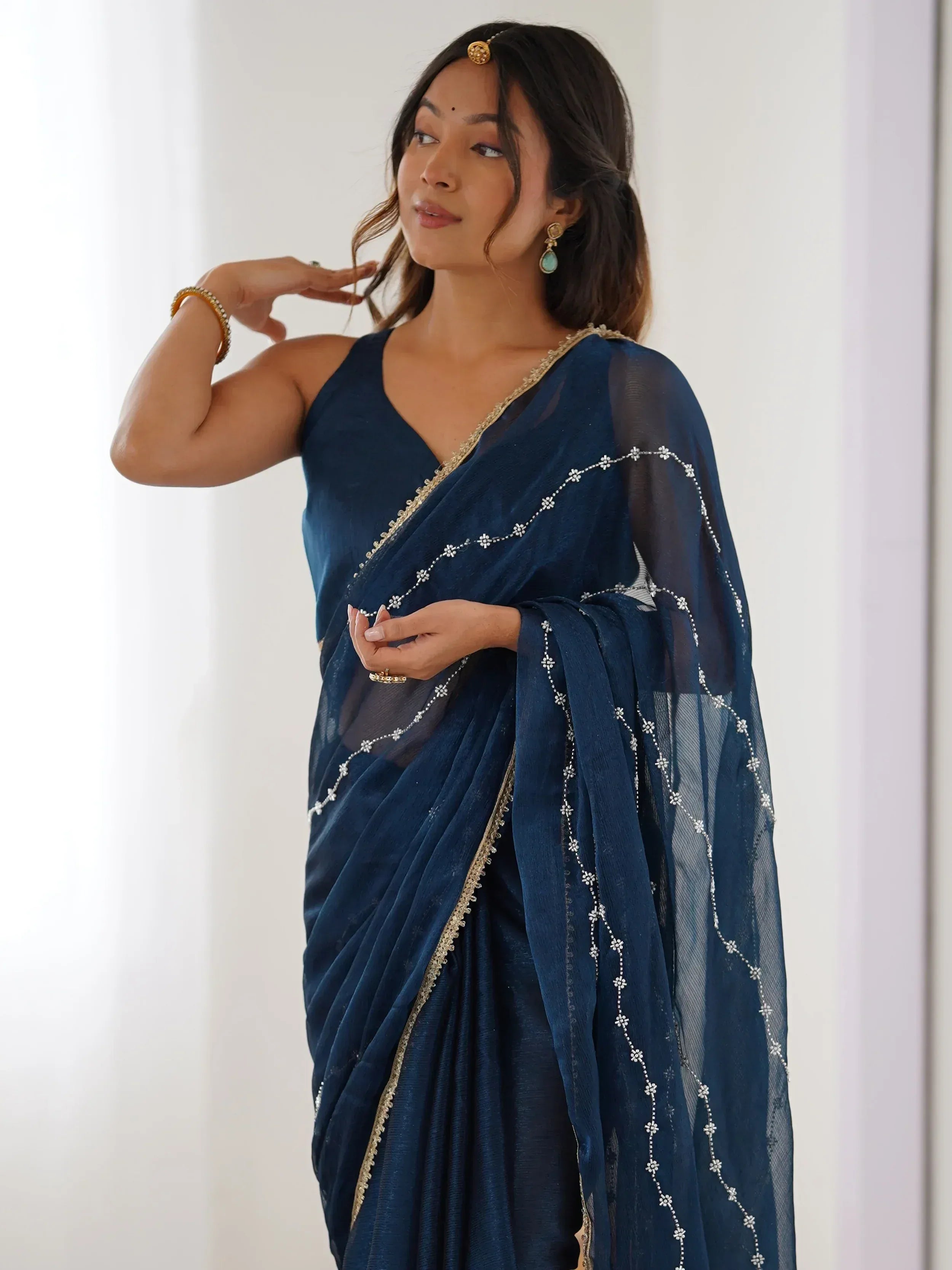 Navy blue embroidered saree with gold trim, styled with traditional jewelry for Indian ethnic wear.