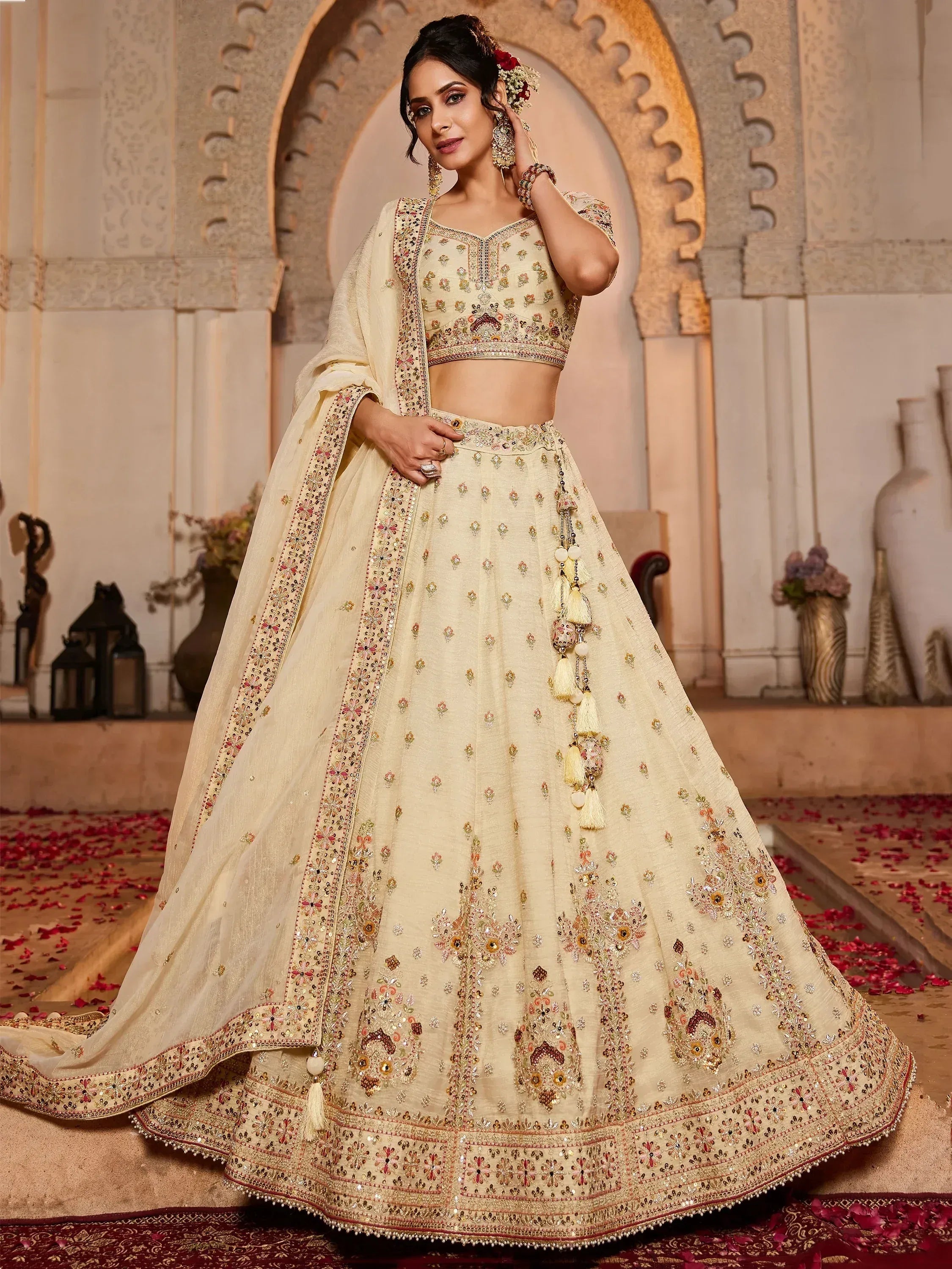 Cream embroidered lehenga choli with floral motifs and tassels, perfect for Indian weddings and festive occasions