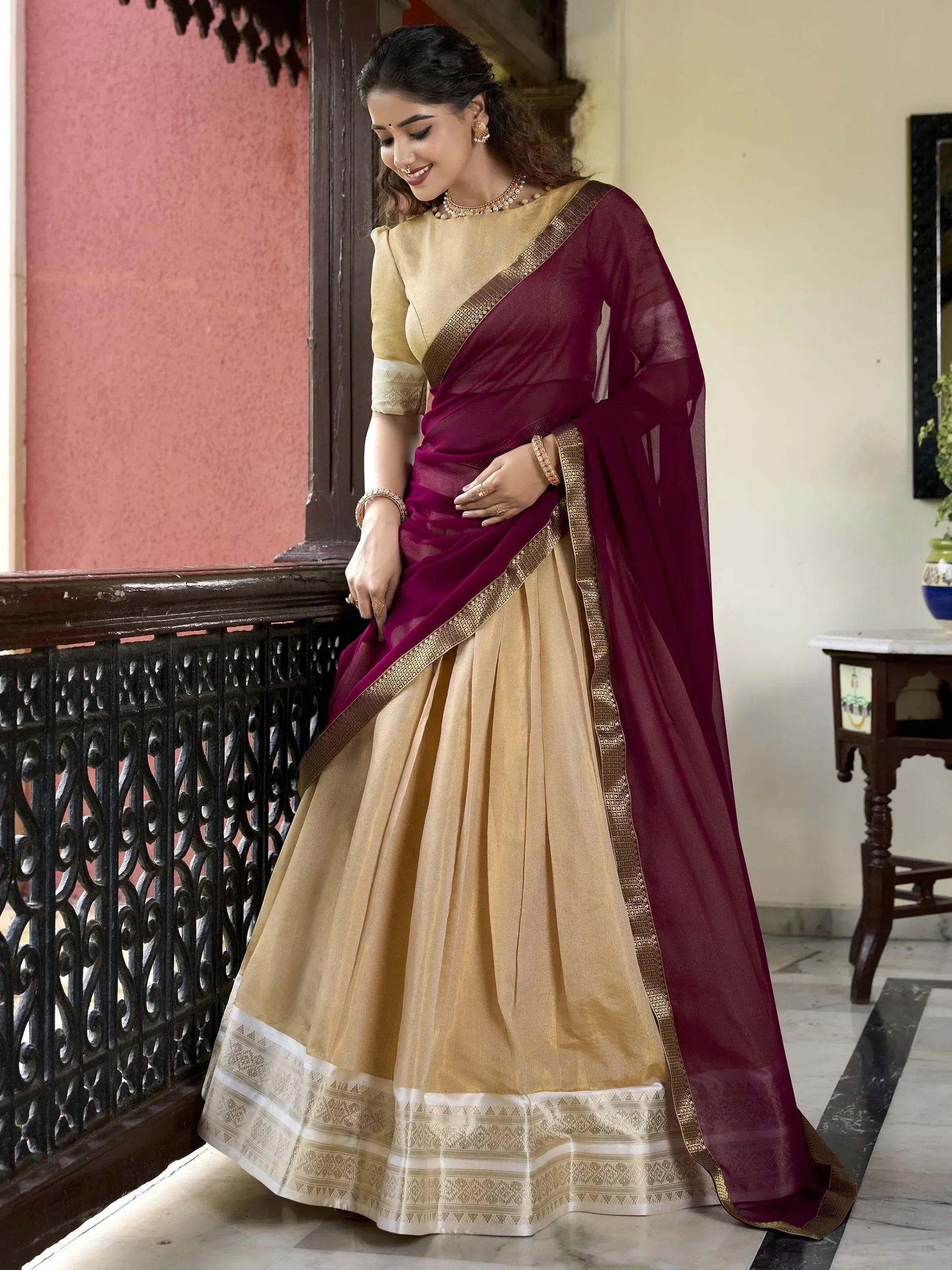 Woman in maroon and gold designer lehenga choli with embroidered border, ethnic Indian wear