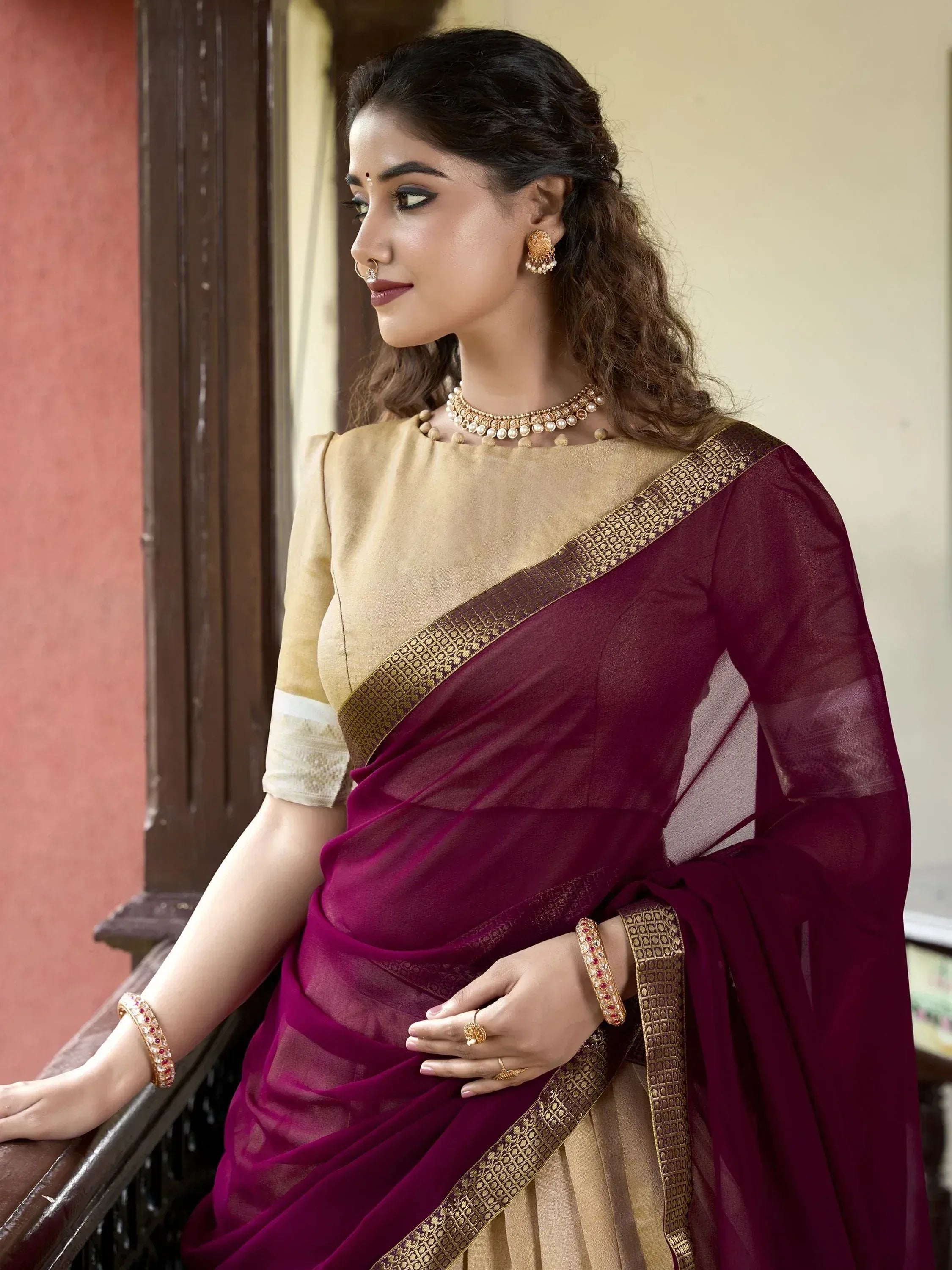 Woman in maroon and gold saree with intricate border, traditional Indian ethnic wear