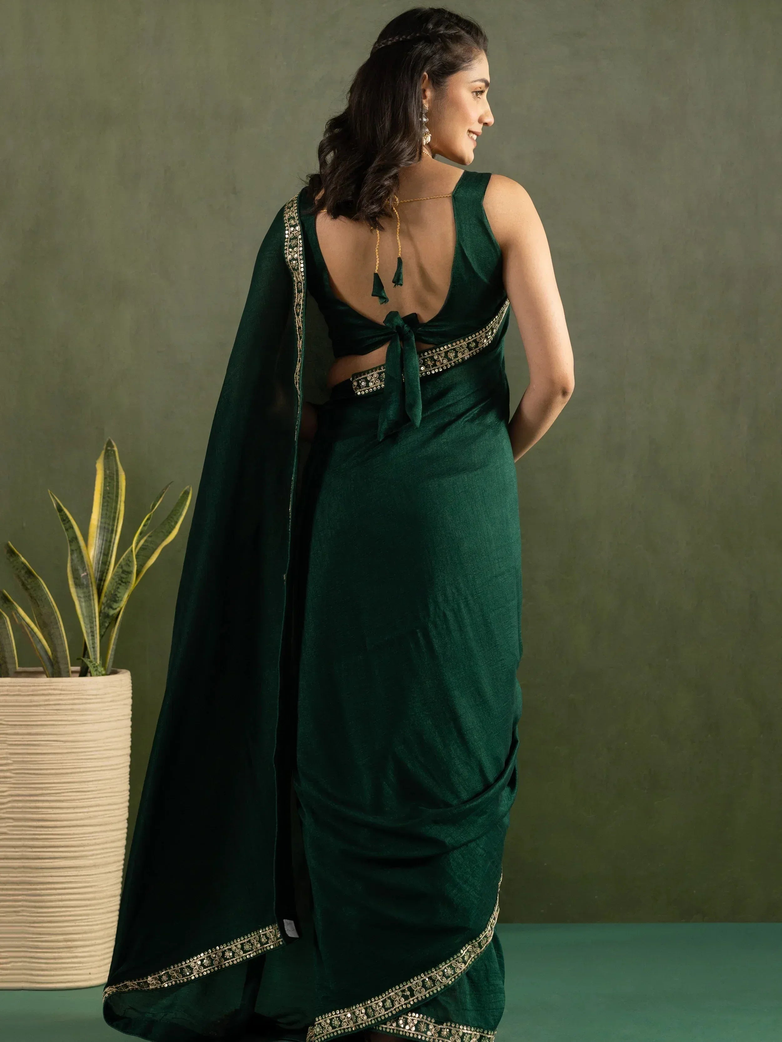 Emerald green saree with gold embroidery, backless blouse, and cape drape for ethnic wear