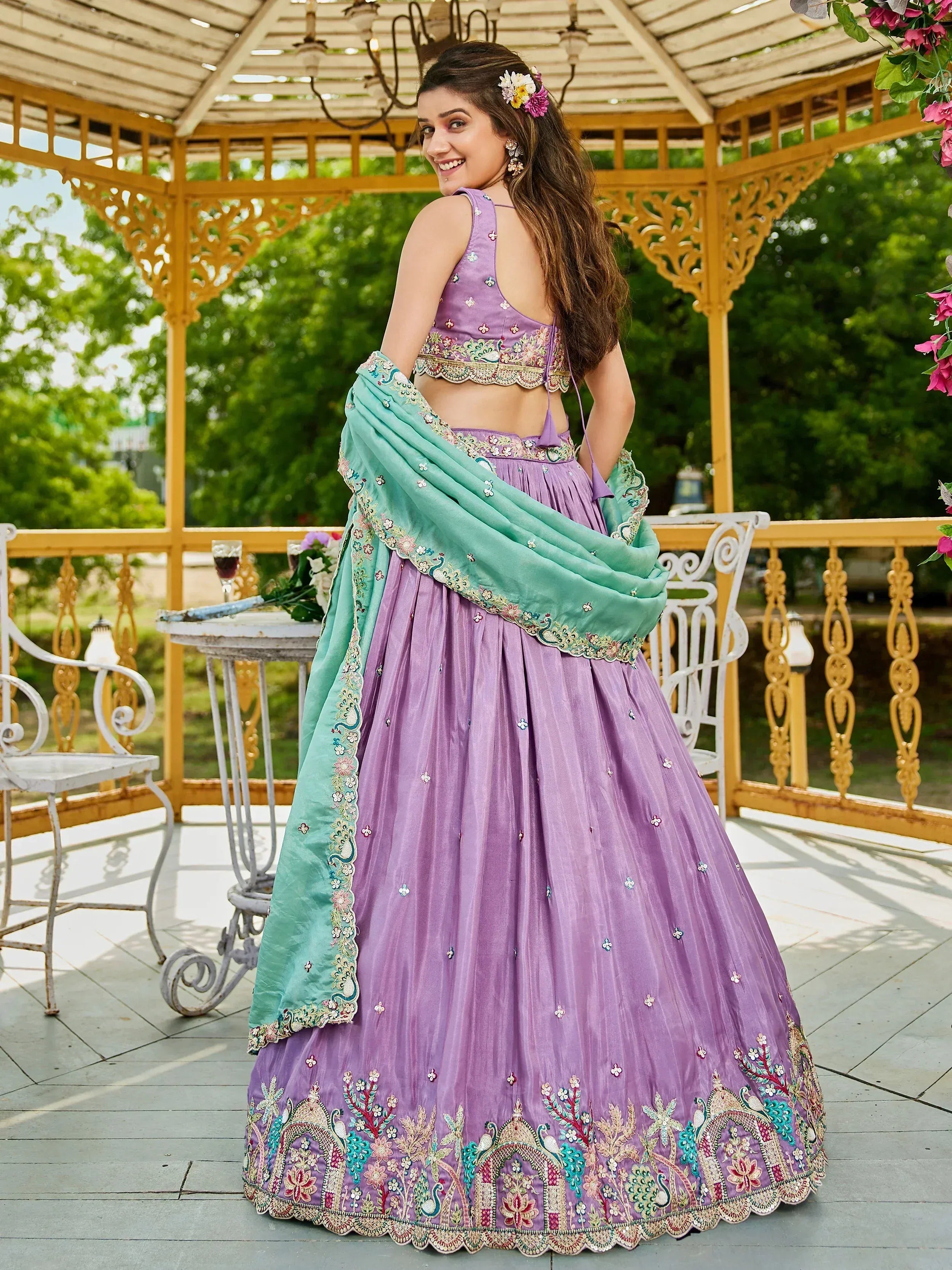Purple embroidered lehenga choli with mint dupatta, floral hair accessories, garden gazebo setting
