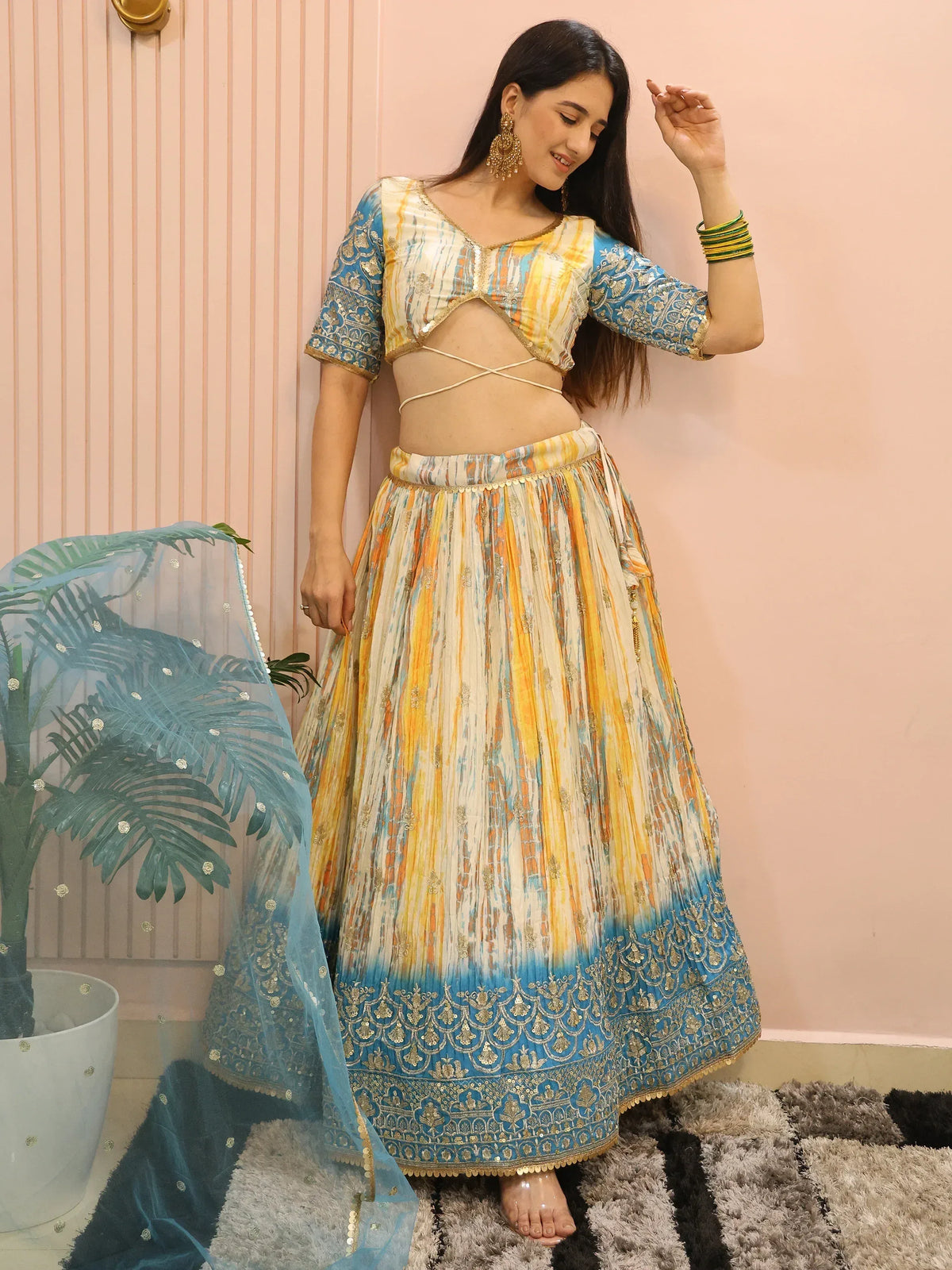 Woman in colorful designer lehenga choli with blue and yellow print, gold embroidery, and matching dupatta