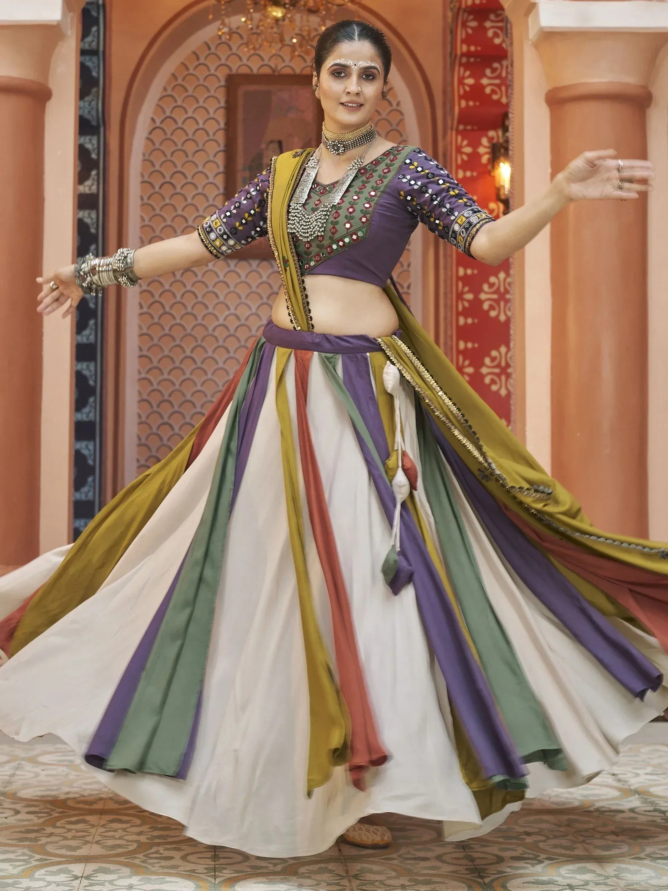 Woman in colorful Indian ethnic lehenga choli with mirror work, dancing in traditional setting