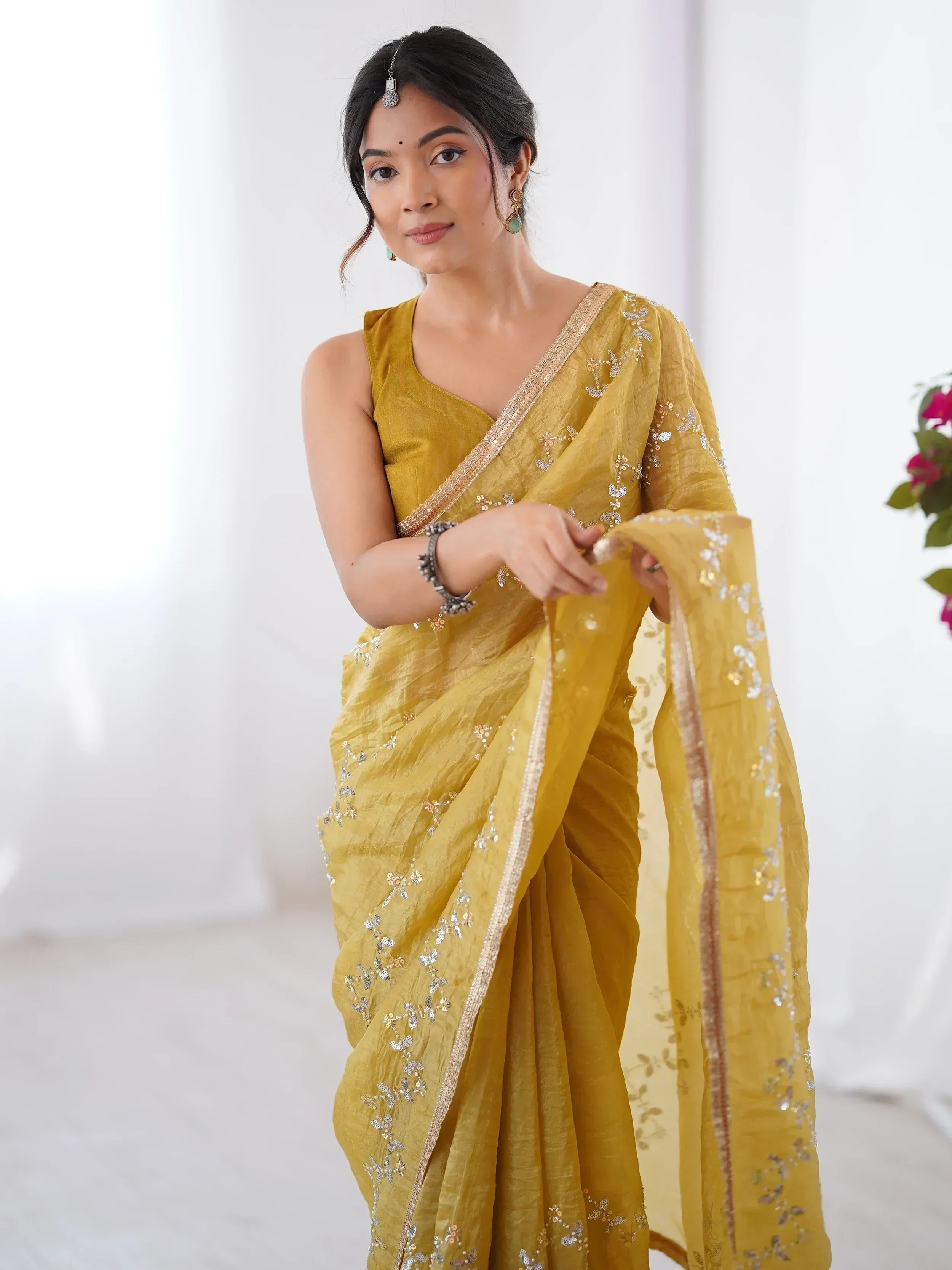 Mustard yellow saree with sequin embroidery and gold border, styled with traditional Indian jewelry