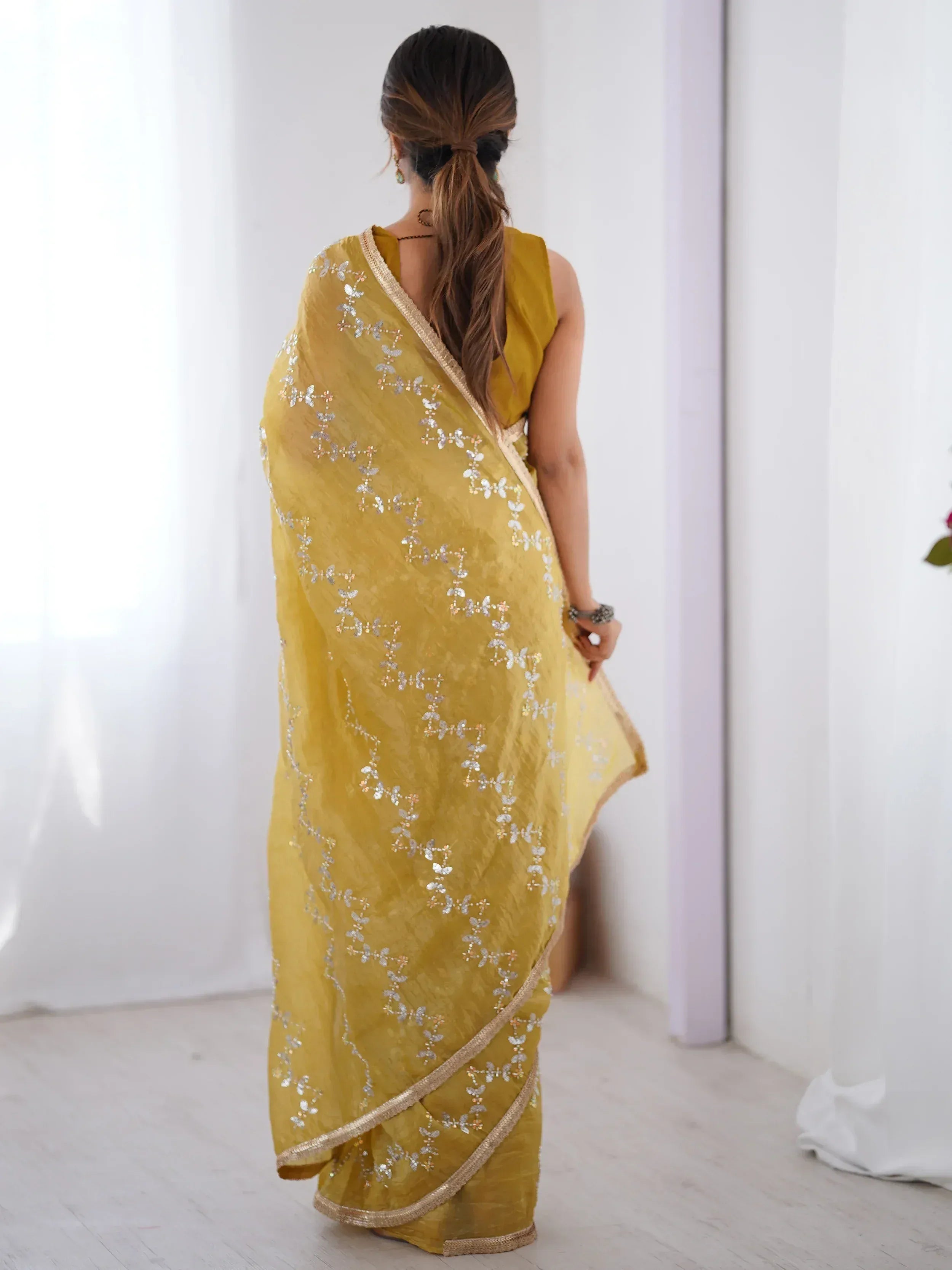 Mustard yellow saree with silver floral embroidery and gold border, styled with sleeveless blouse
