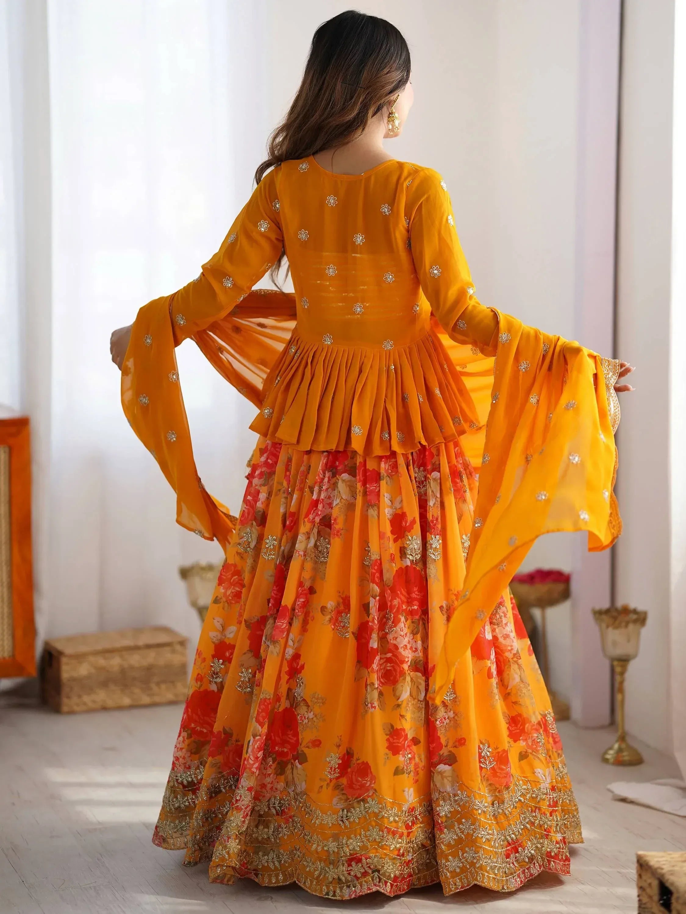 Woman in vibrant orange floral lehenga choli with gold embroidery, showcasing ethnic Indian wear