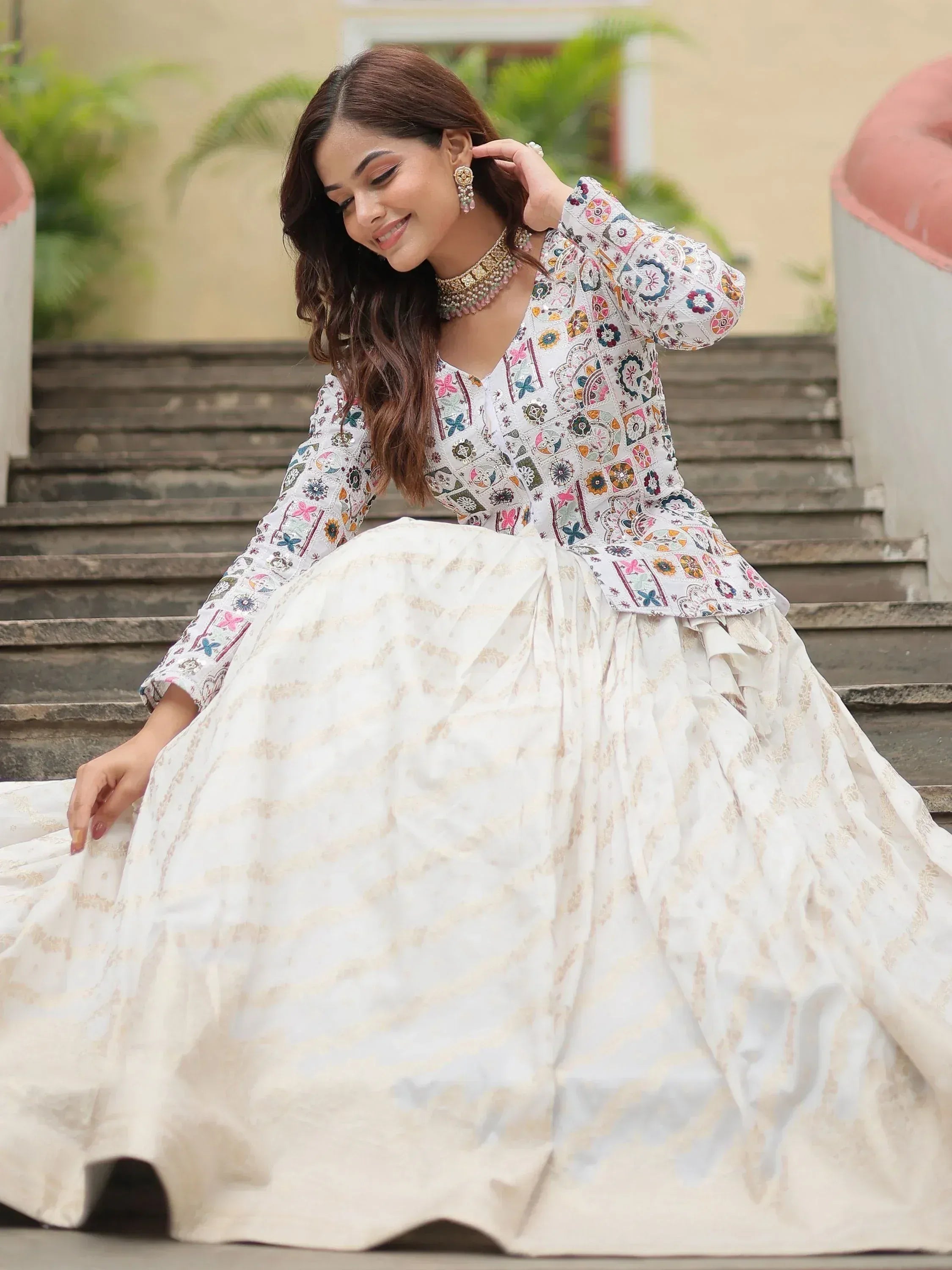 Woman in white embroidered ethnic gown with floral top, perfect for Indian occasions and festive wear.
