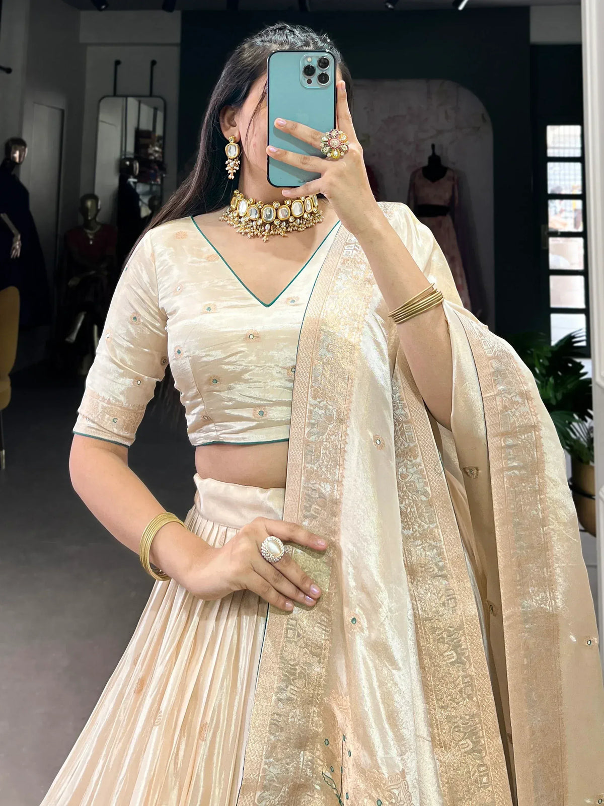 Elegant cream lehenga choli with gold embroidery, paired with traditional jewelry for Indian ethnic wear