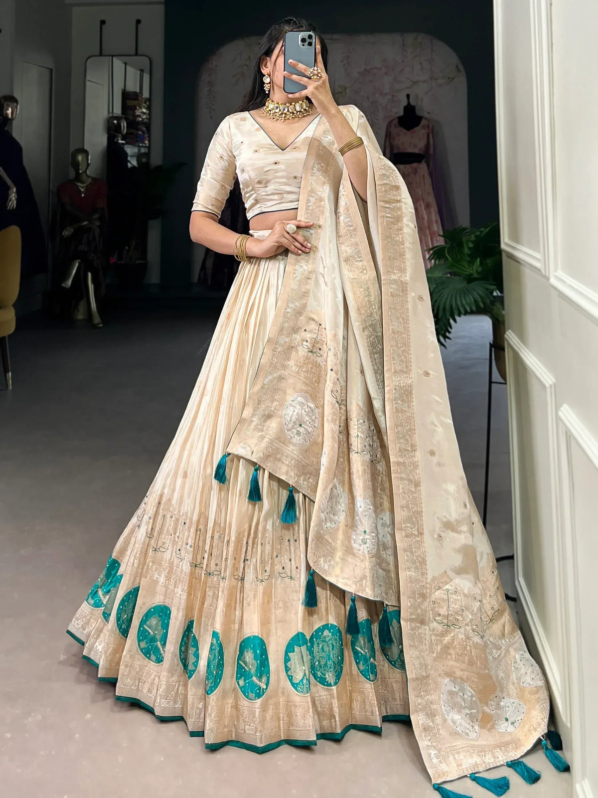 Elegant beige lehenga choli with teal embroidery and tassels, perfect for Indian ethnic wear occasions