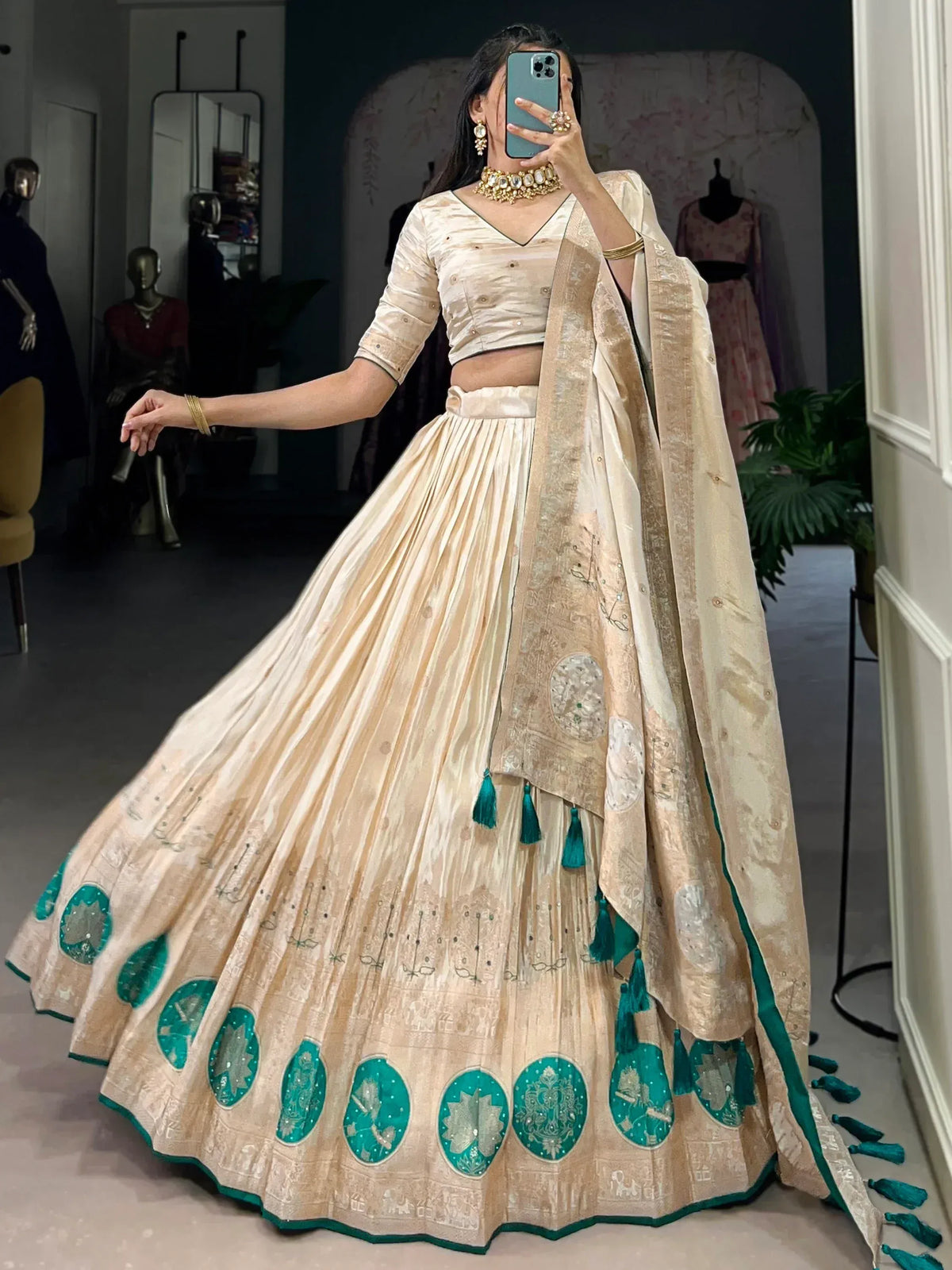 Cream and emerald green designer lehenga choli with intricate embroidery and tassels, perfect for Indian ethnic wear.