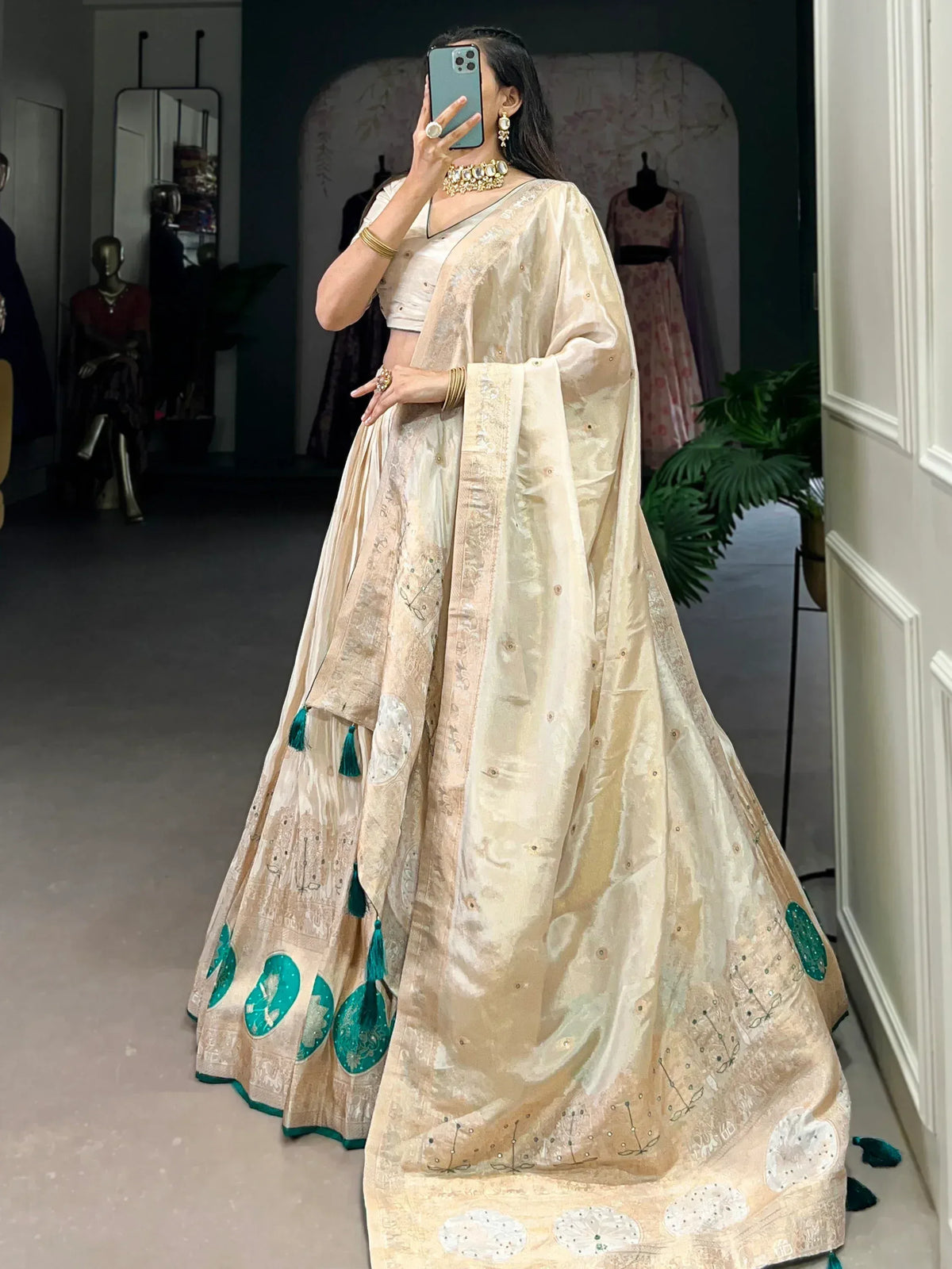 Elegant cream lehenga choli with teal embroidery and tassels, perfect for Indian ethnic wear occasions.