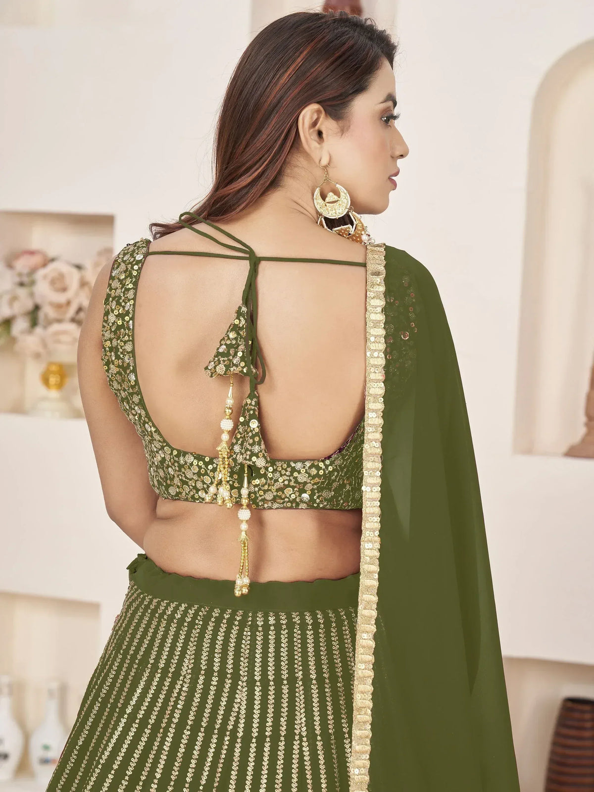 Olive green designer lehenga choli with sequin work, backless blouse, and tassel details