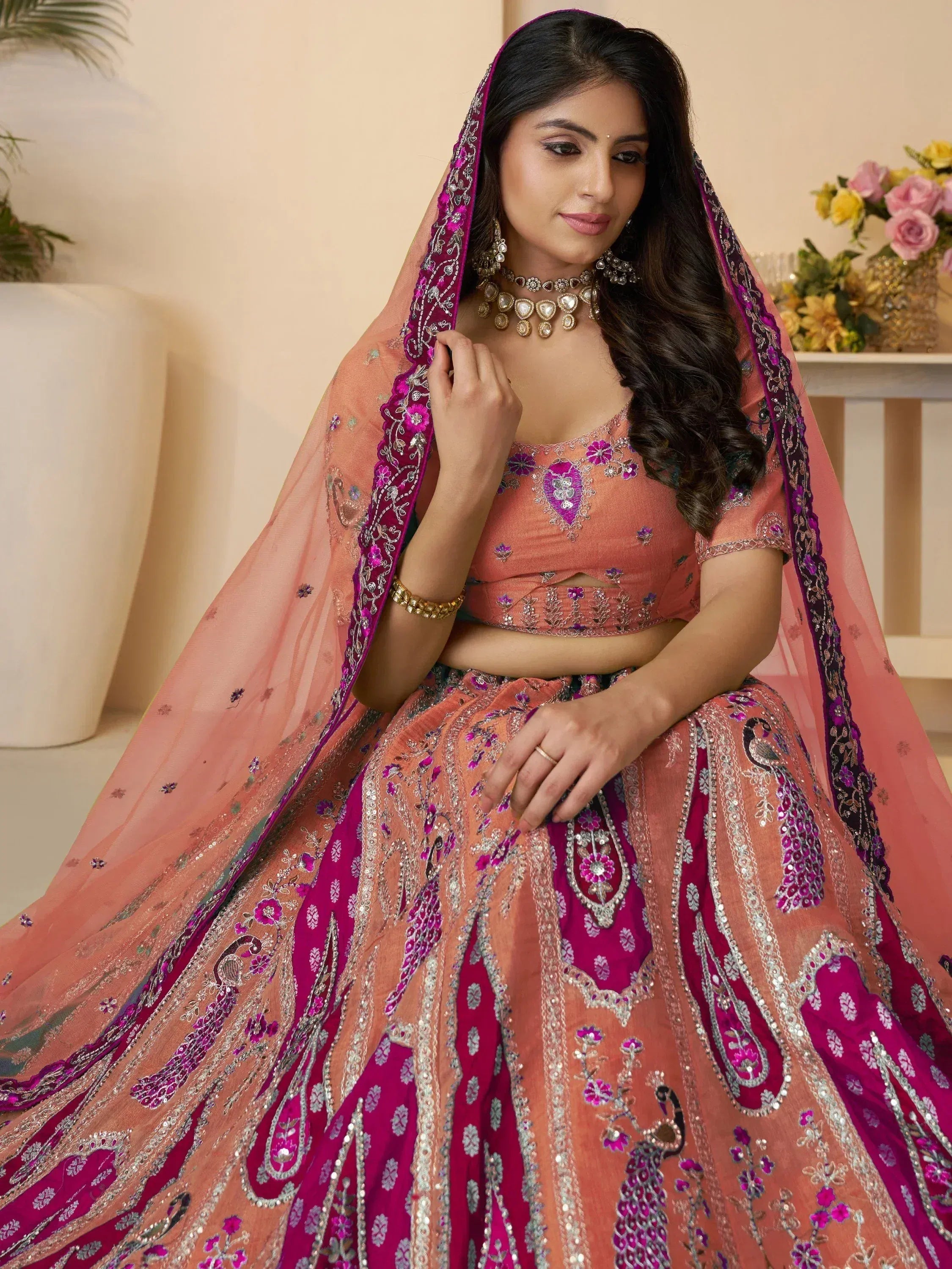 Elegant peach and magenta embroidered lehenga choli with peacock motifs and sheer dupatta, perfect for Indian weddings.