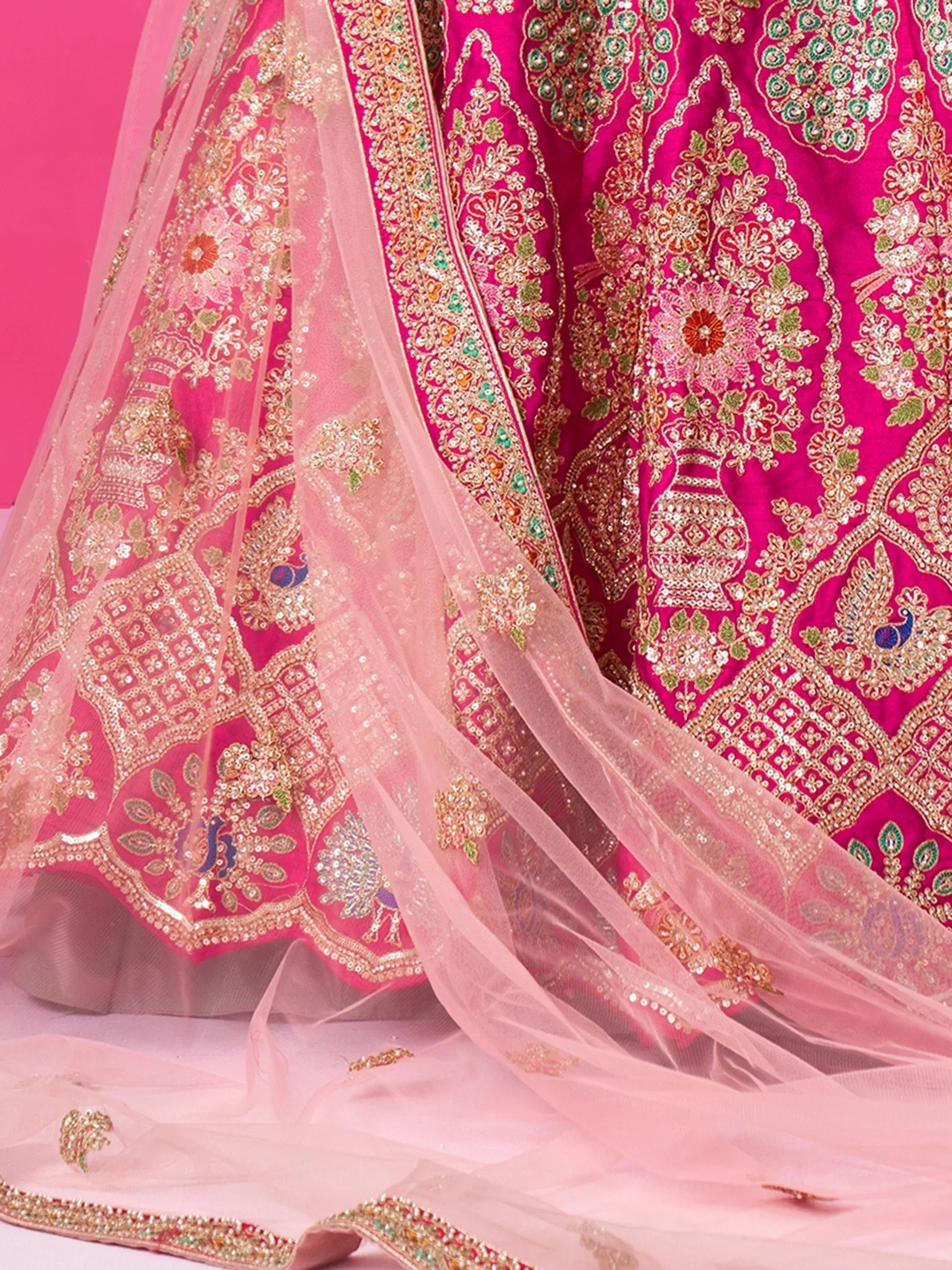 Pink designer lehenga choli with intricate gold embroidery and sheer dupatta, perfect for Indian weddings and festive occasions.