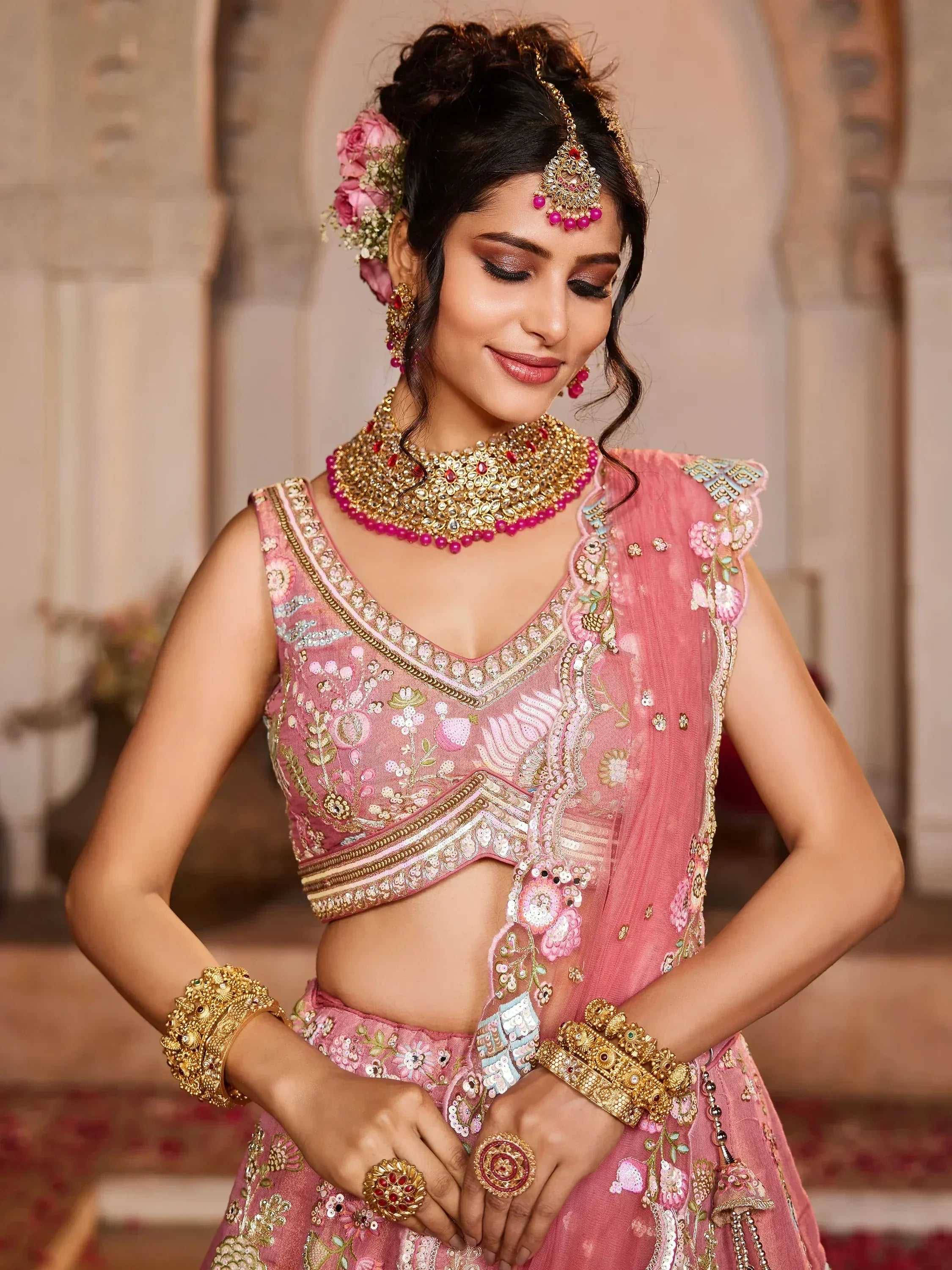 Pink embroidered lehenga choli with gold jewelry, perfect for Indian weddings and festive occasions