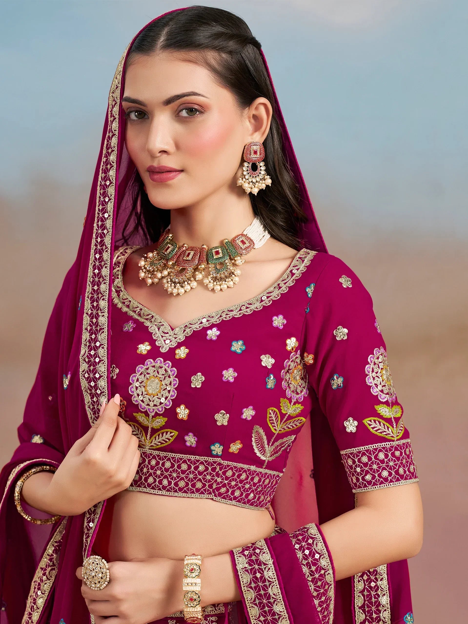 Elegant maroon ethnic blouse with floral embroidery and gold detailing, paired with matching dupatta and traditional jewelry.