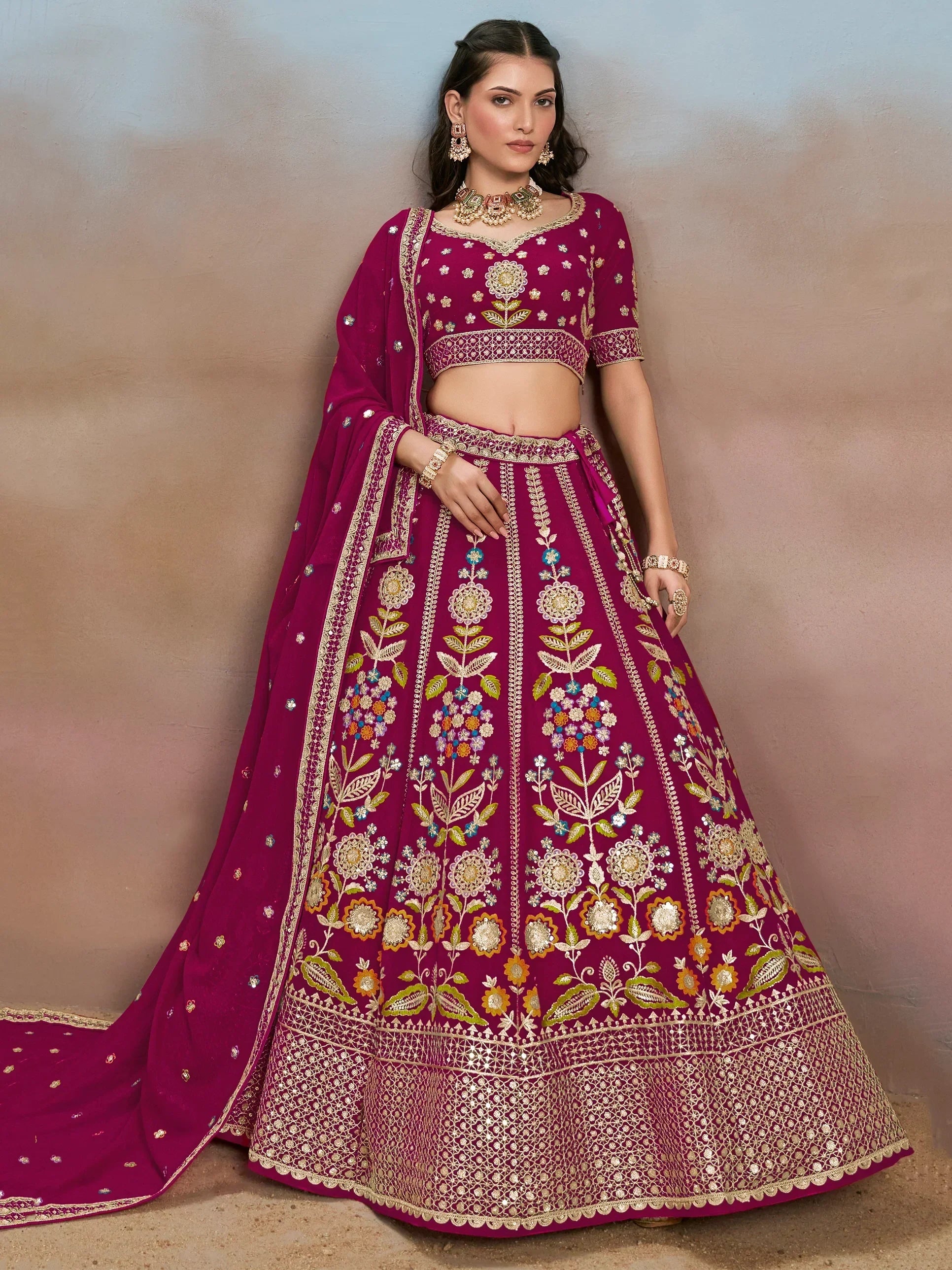 Elegant magenta lehenga choli with intricate floral embroidery and gold detailing, perfect for Indian weddings and festive occasions.