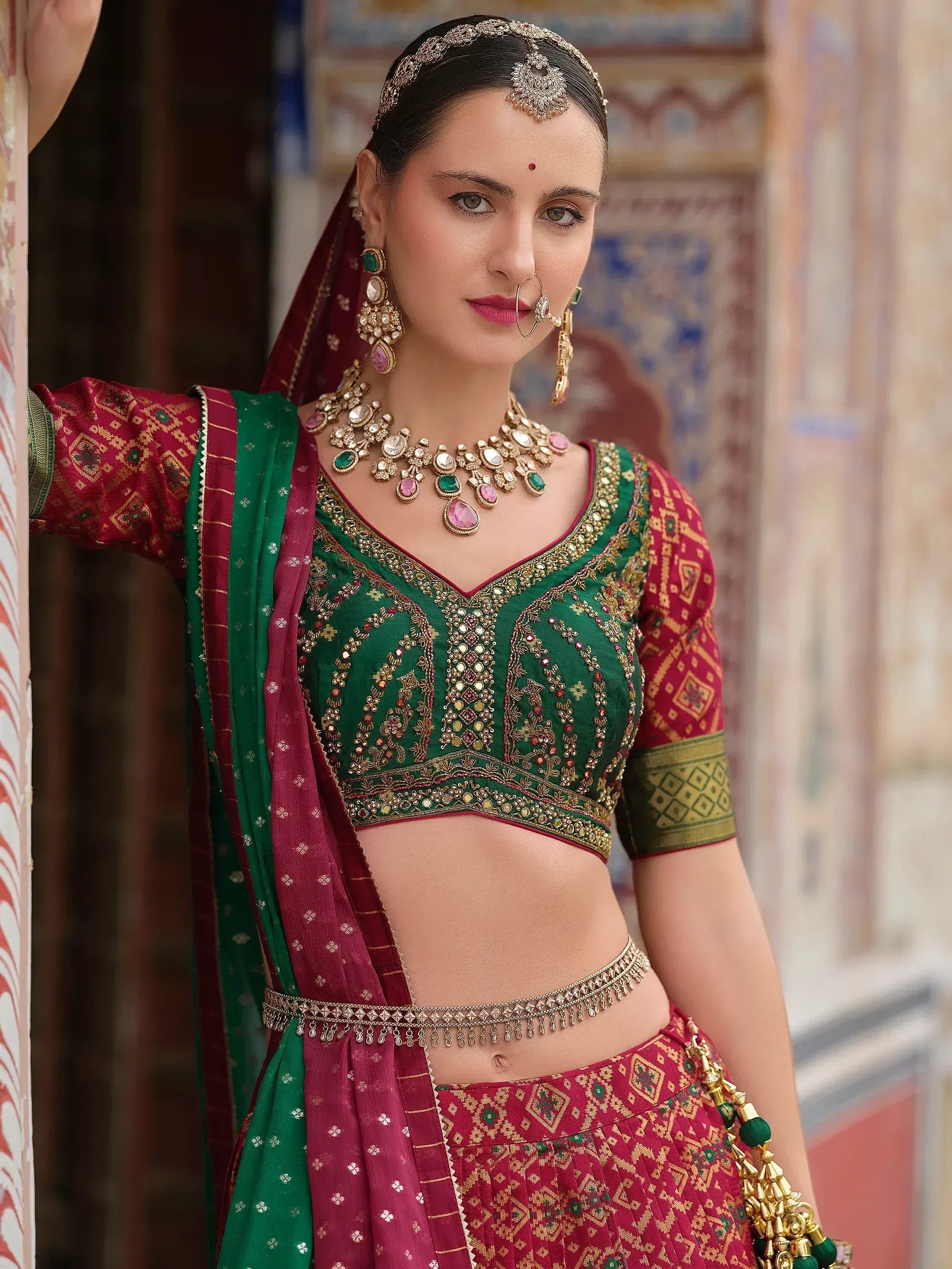 Green and maroon embroidered lehenga choli with traditional jewelry, perfect for Indian ethnic wear.